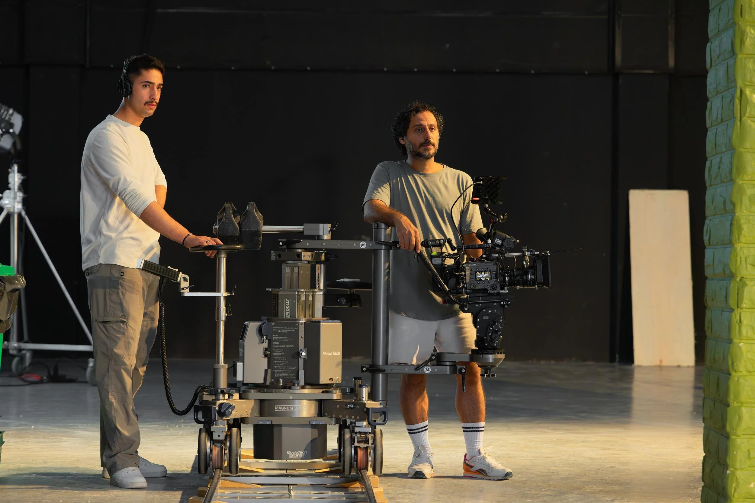 Ahlan Simsim unit still: Two crew members stand on a studio set with a camera mounted on a tracking dolly.