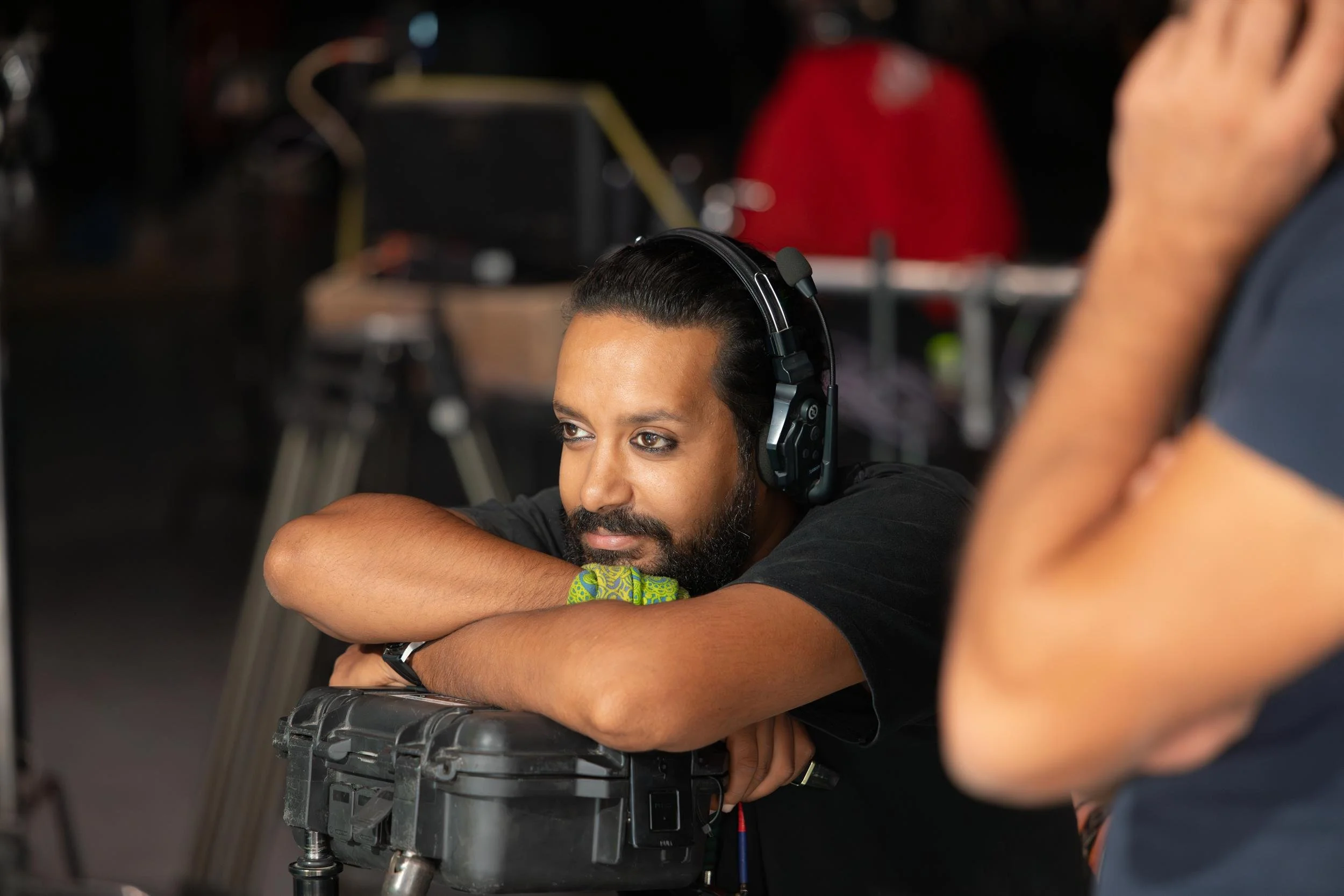 Ahlan Simsim unit still: a crew member with a headset leans his arms on an equipment case.