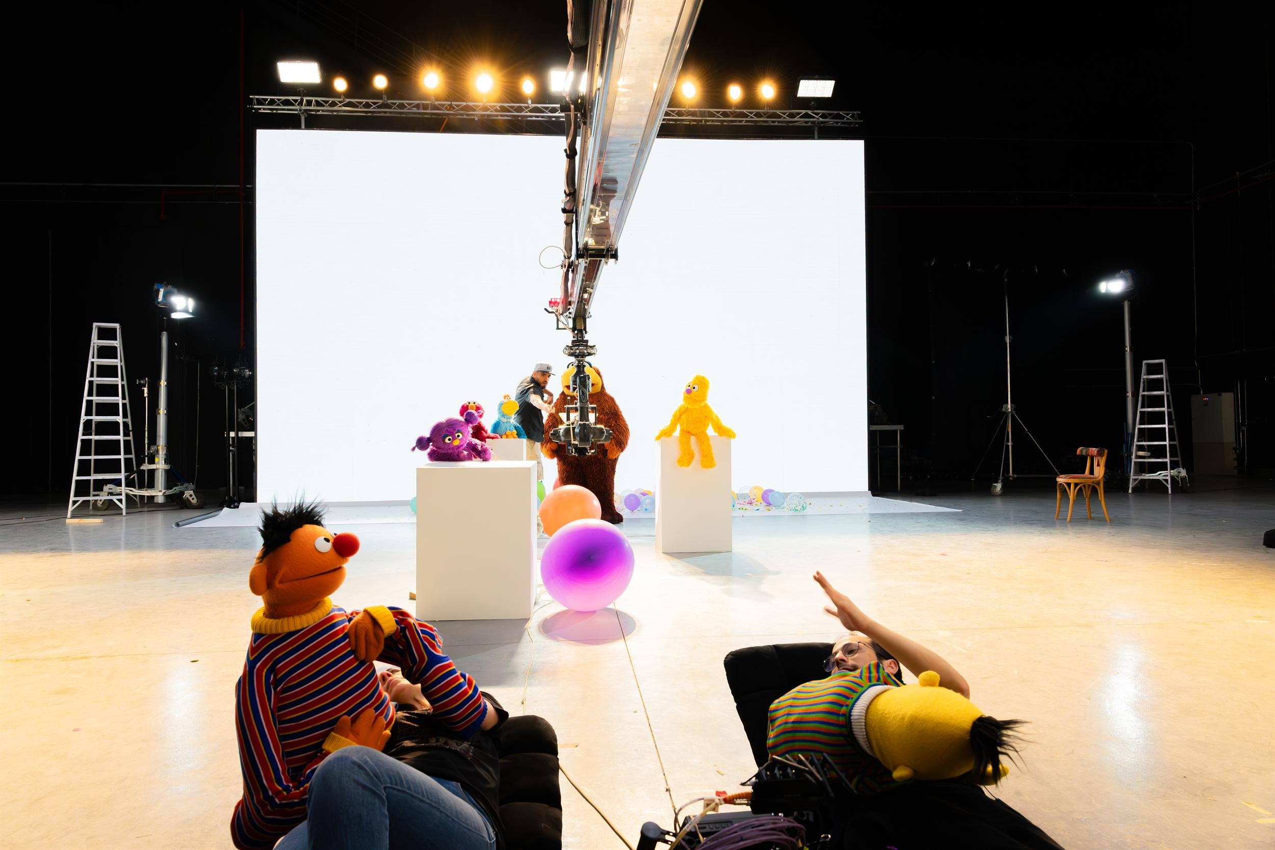 Ahlan Simsim unit still: puppeteers lie on the floor with Ernie and Bert facing a white screen and other Muppets.