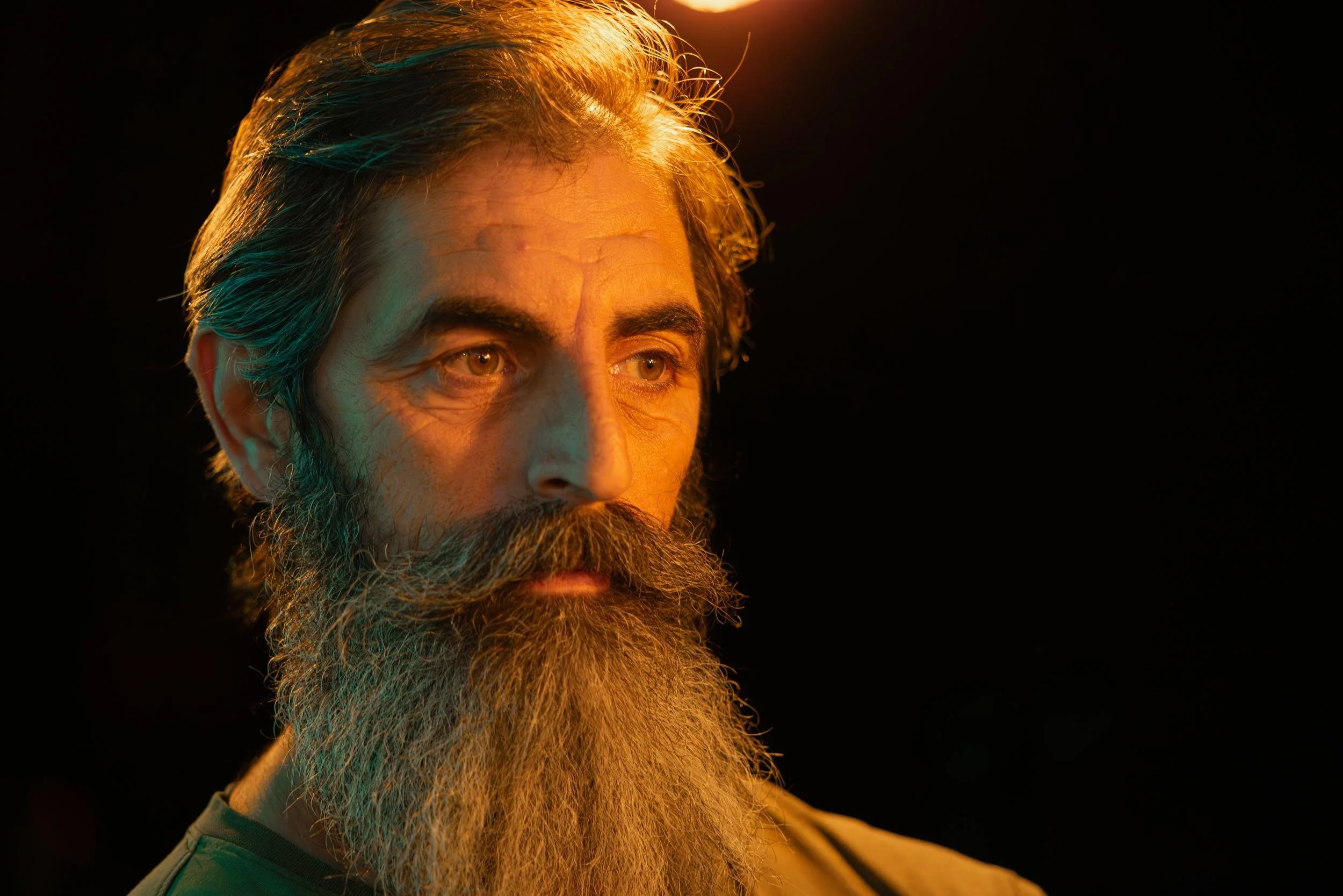 Ahlan Simsim unit still: close-up of a man with a long grey beard under orange and green lighting.