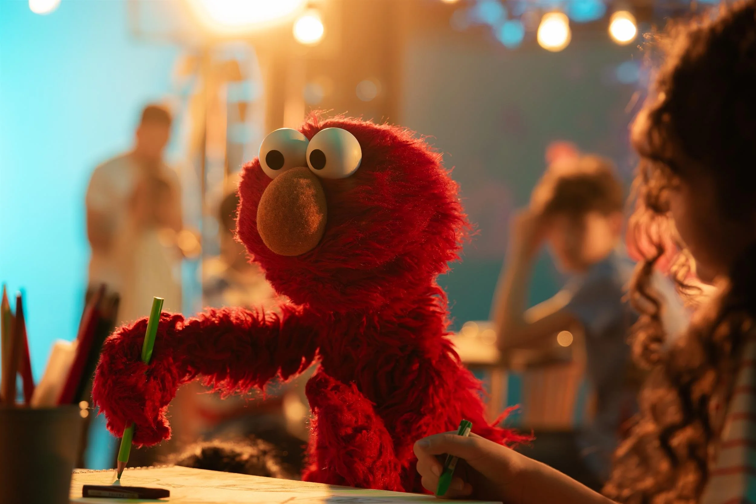 Ahlan Simsim unit still: Elmo writes with a pencil while crew work on set.