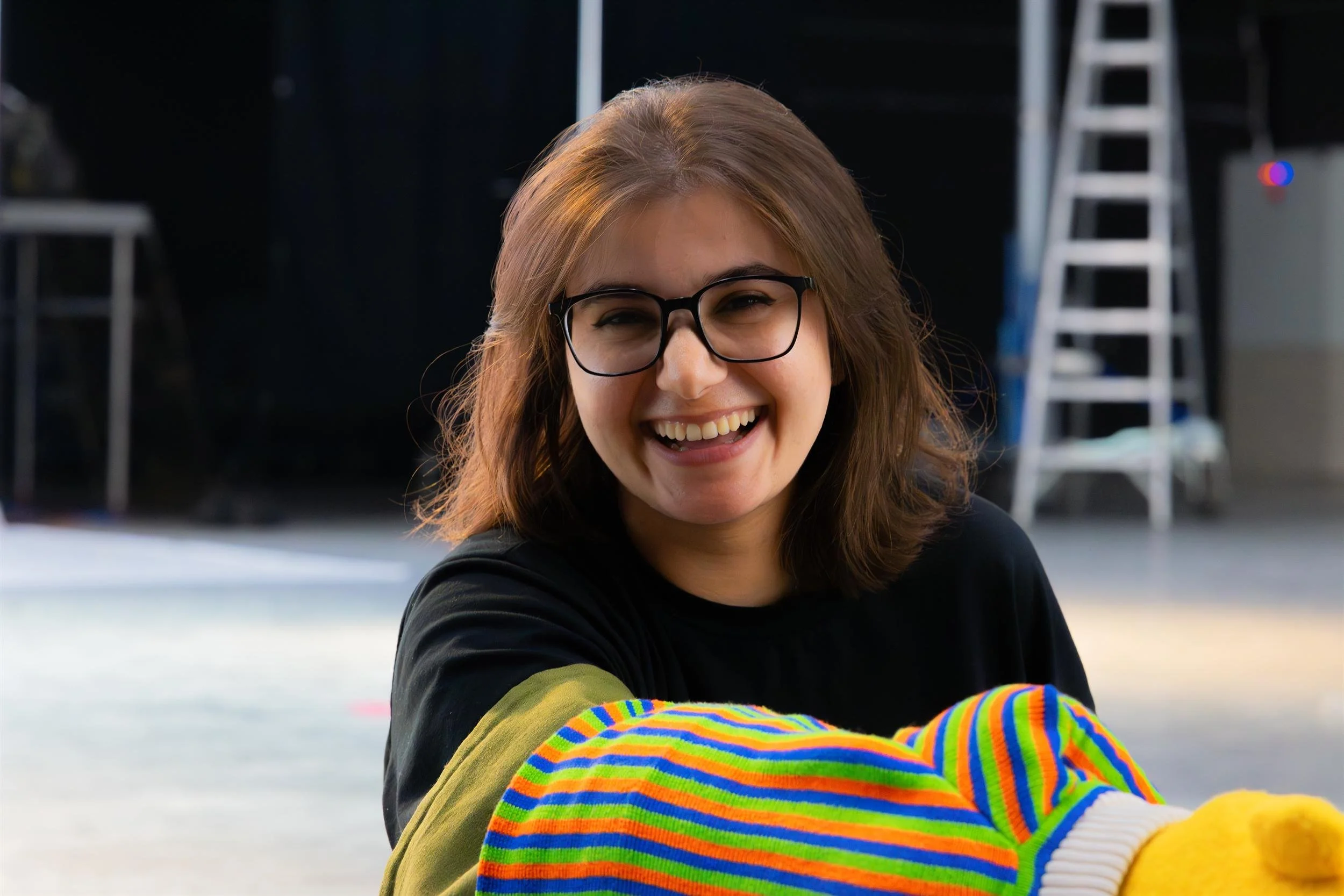 Ahlan Simsim unit still: a crew member laughs while working with a Muppet on a studio set.