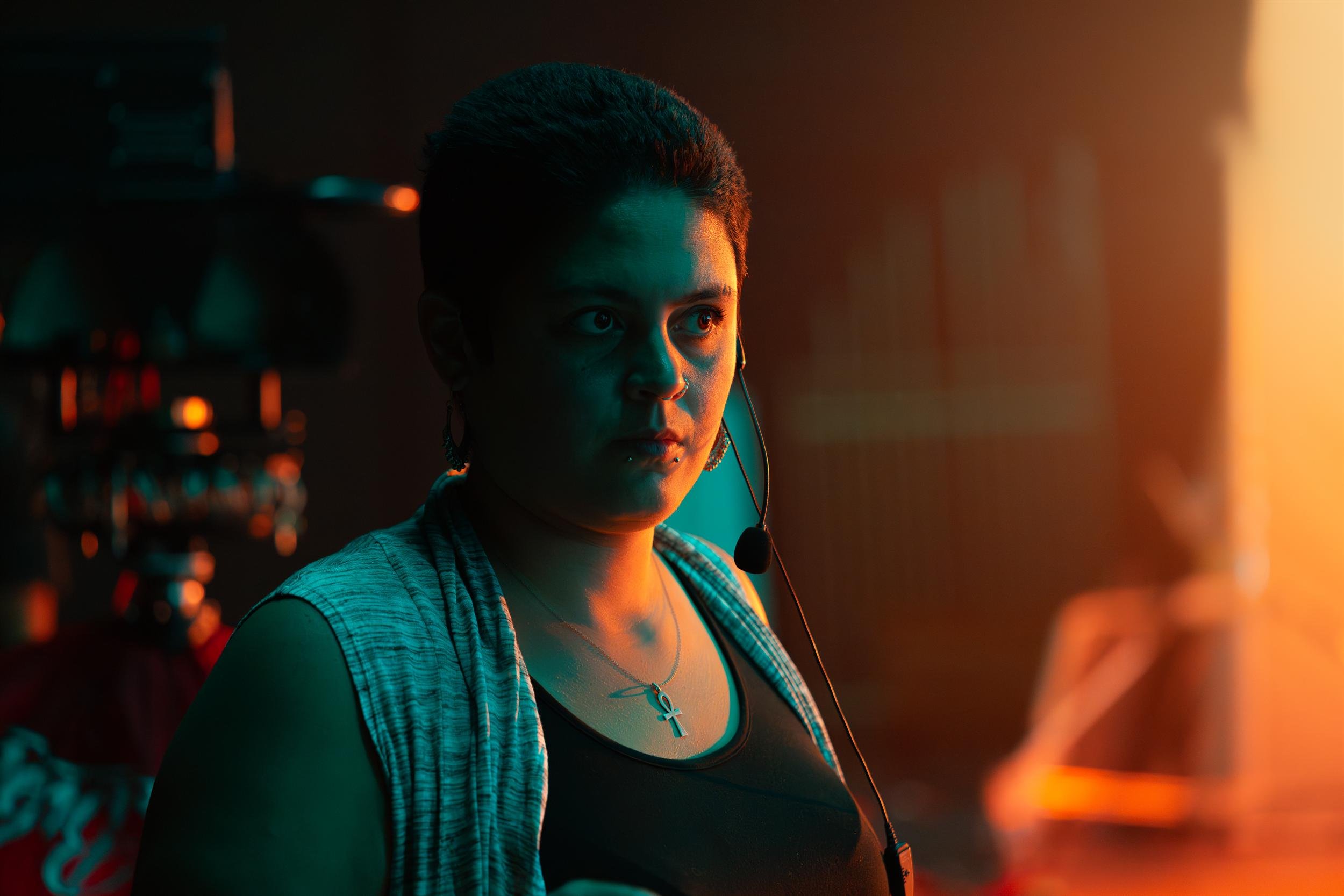 Ahlan Simsim unit still: a crew member in a headset looks off-camera under orange and teal light.
