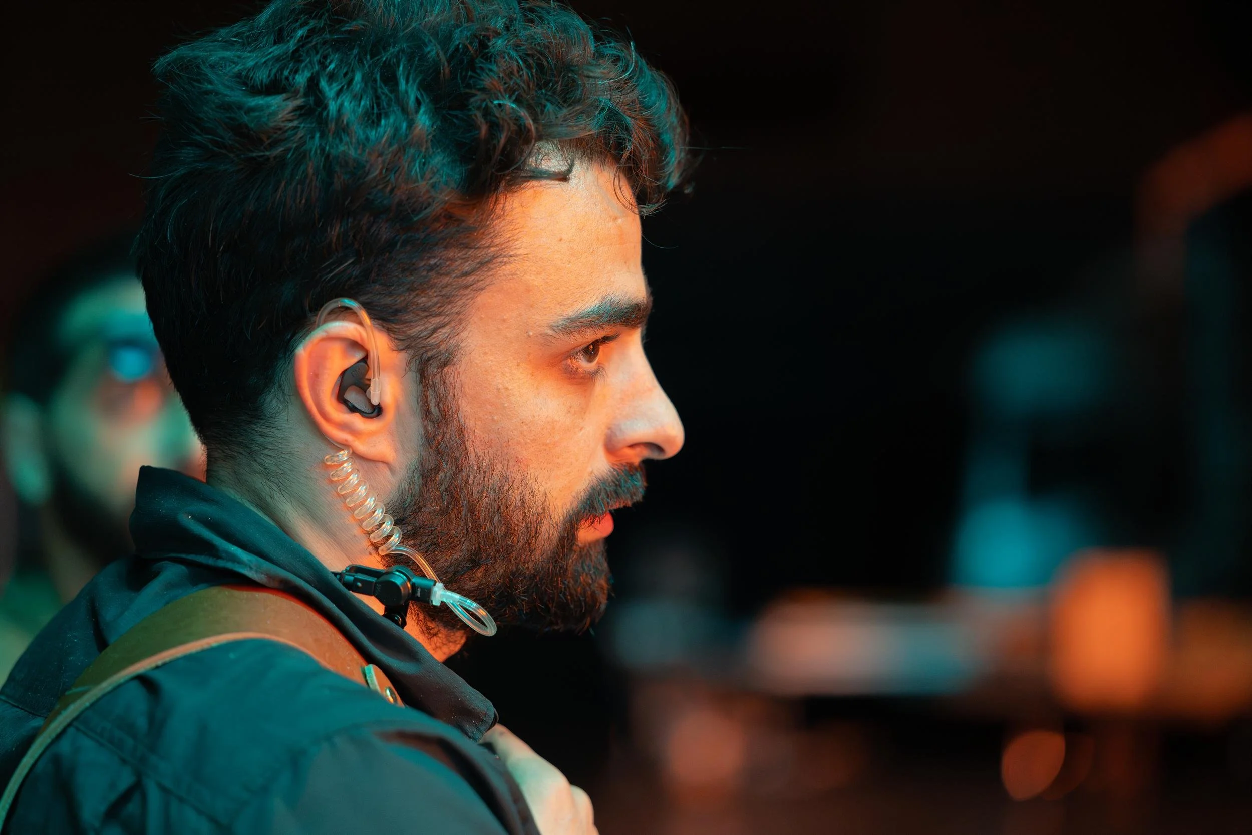 Ahlan Simsim unit still: a crew member with a coiled earpiece looks on under orange studio light.