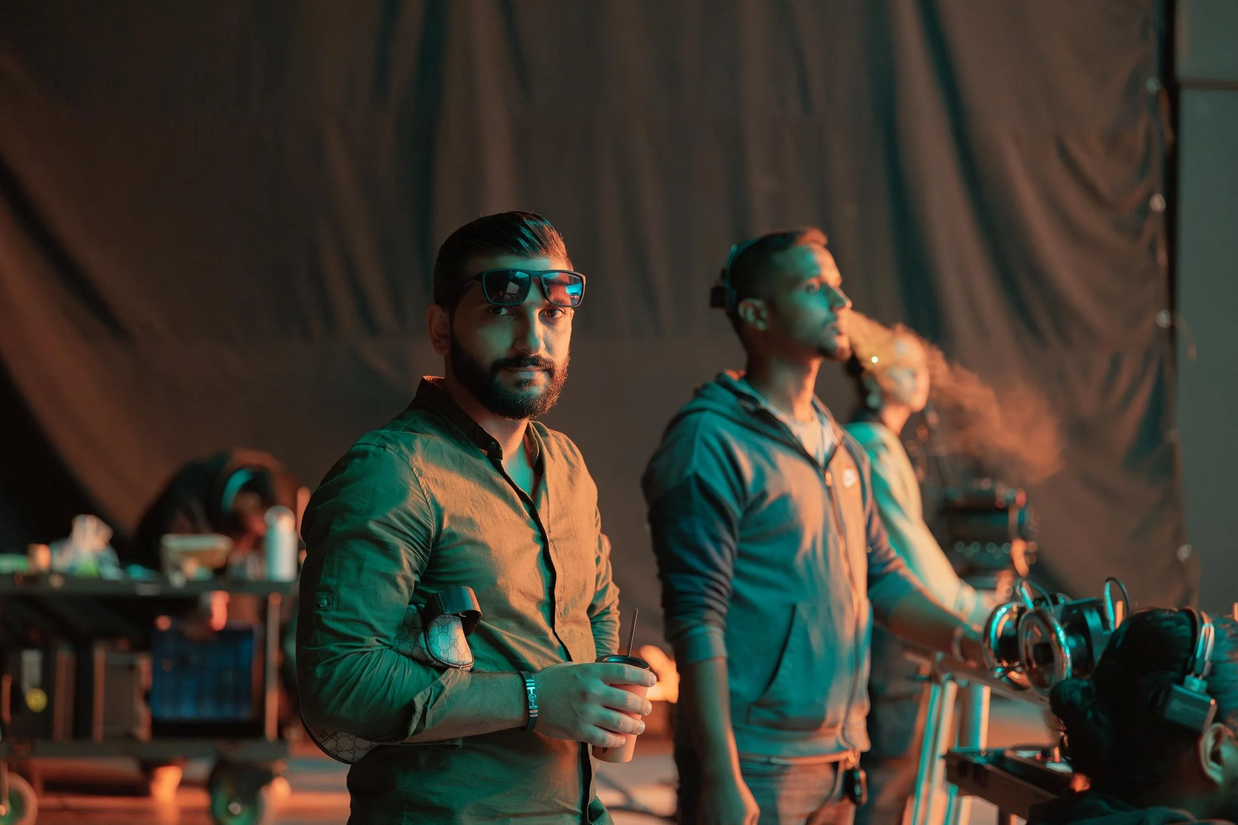 Ahlan Simsim unit still: two crew members on a dim set, one holding a coffee cup, the other in a headset.