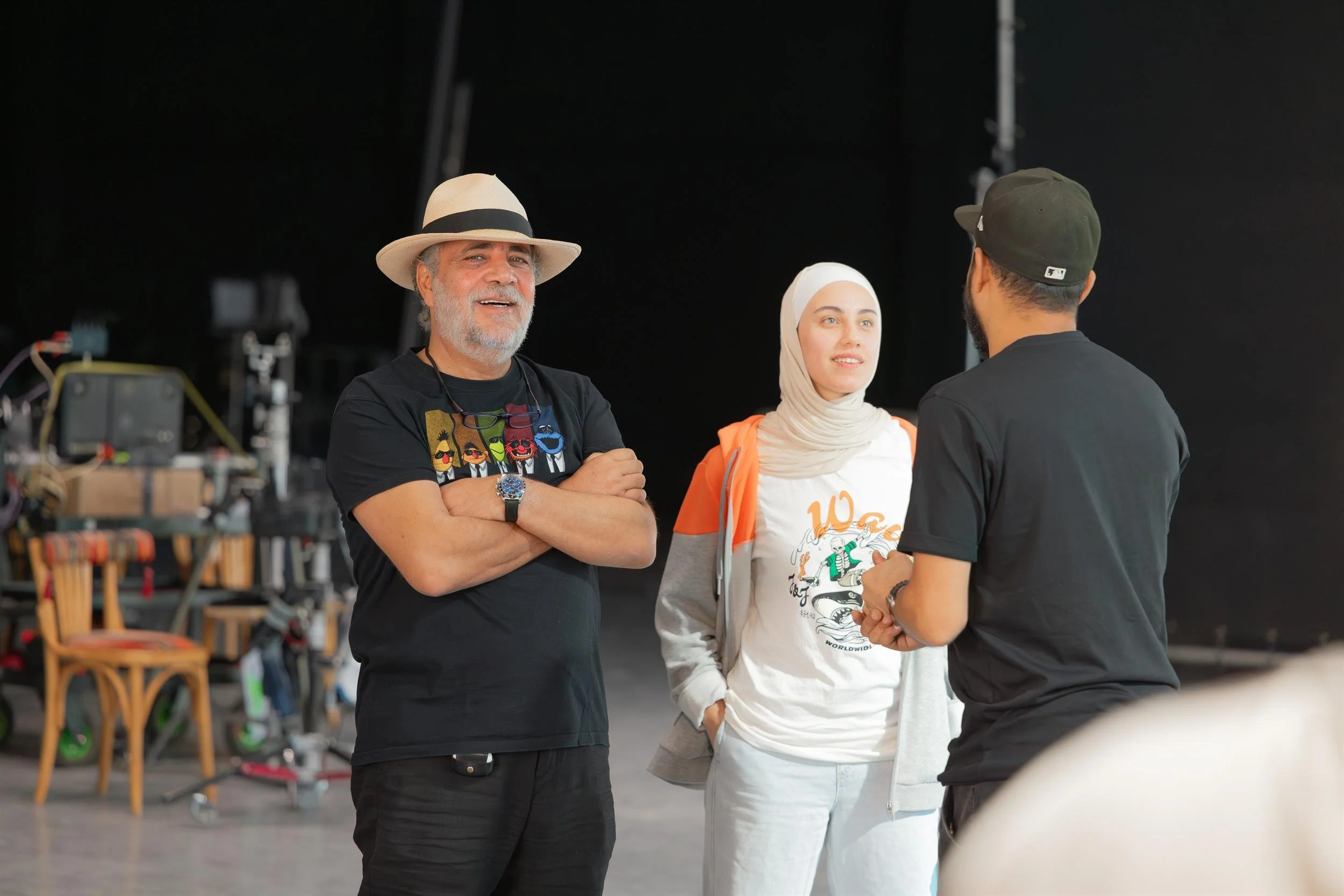 Ahlan Simsim unit still: three crew members talk together on a production set.