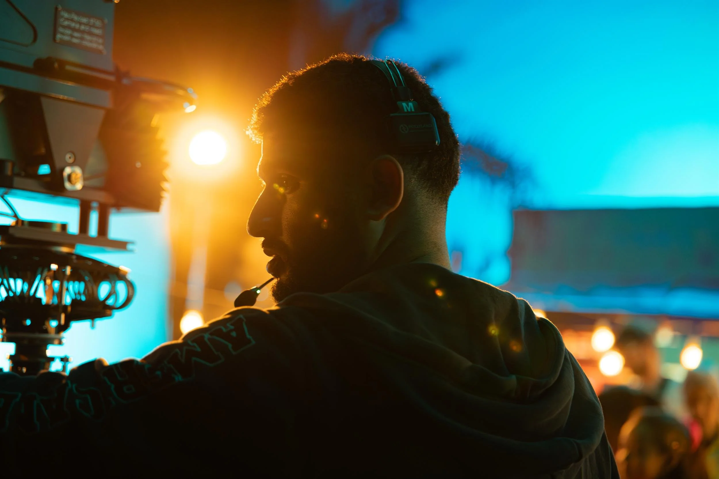 Ahlan Simsim unit still: a crew member in a headset stands behind a camera rig on a colorful night set.