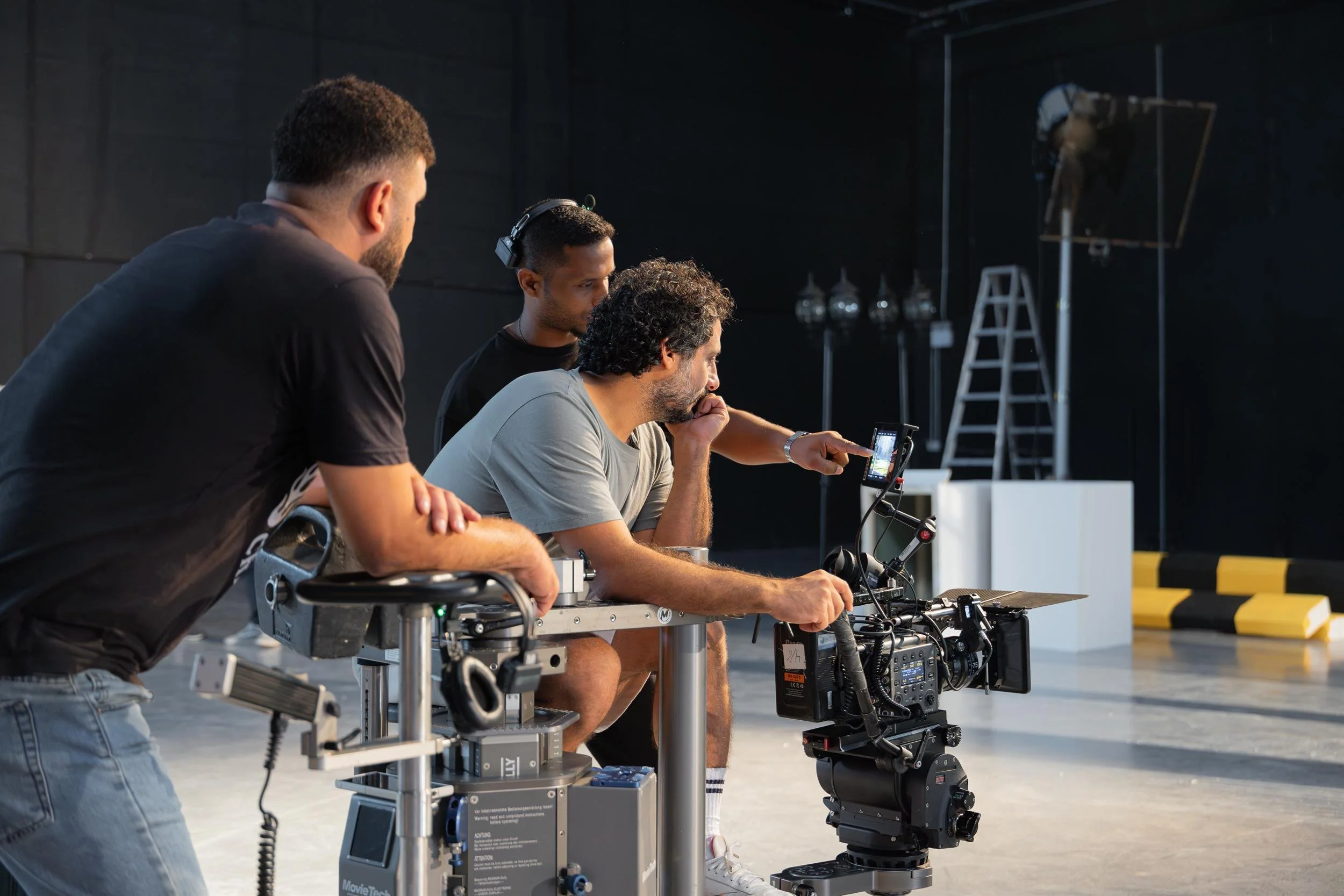 Ahlan Simsim unit still: Three crew members huddle around a camera to review footage on a small monitor.