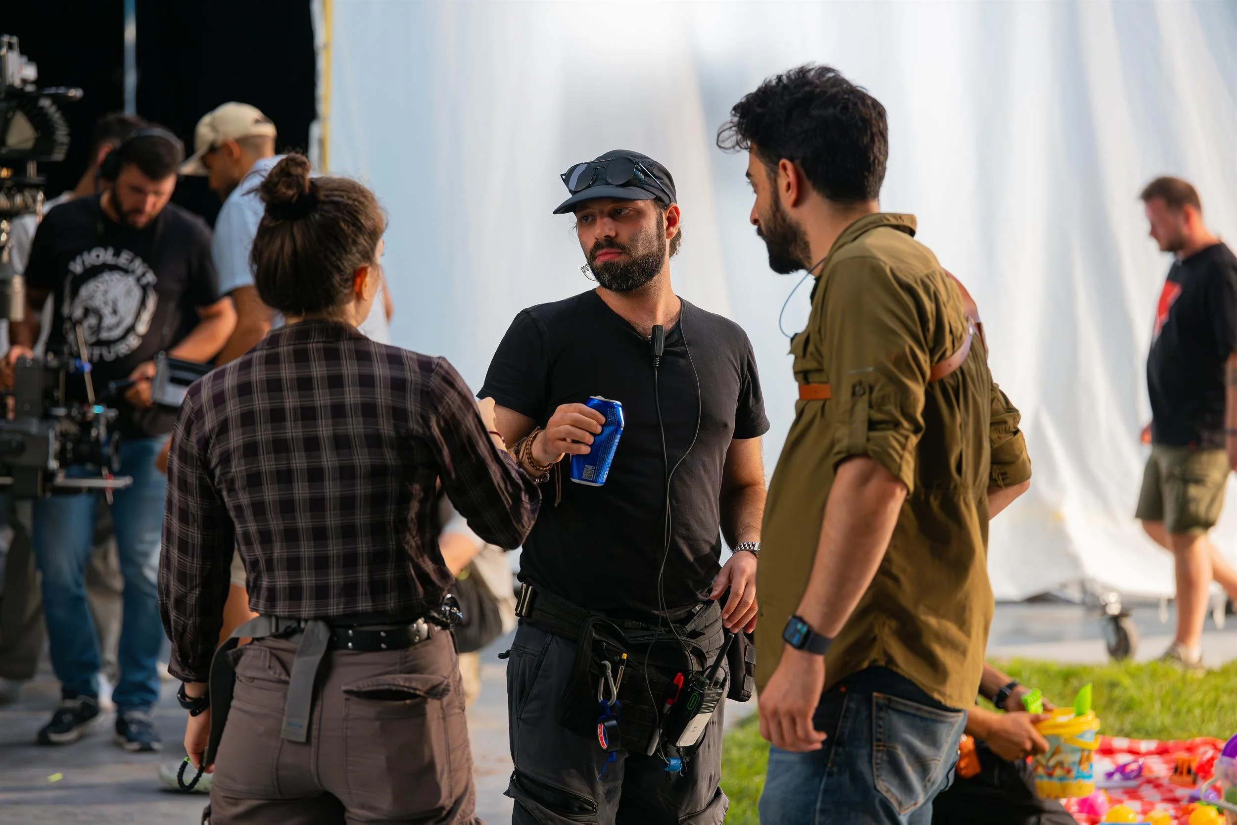 Ahlan Simsim unit still: three crew members talk on set beside a camera and a picnic blanket.