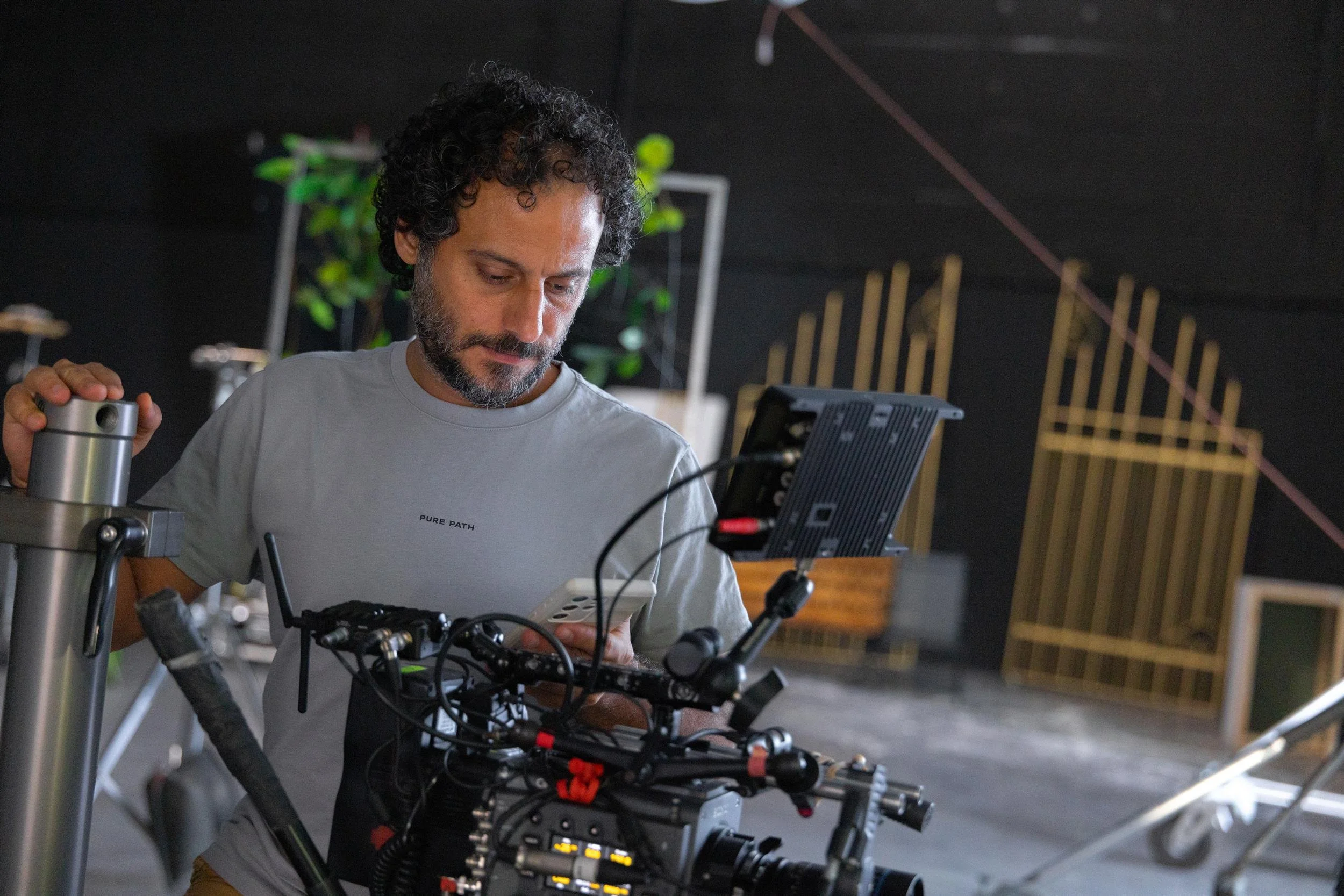 Ahlan Simsim unit still: a crew member checks a phone behind a cinema camera with a golden gate in the background.
