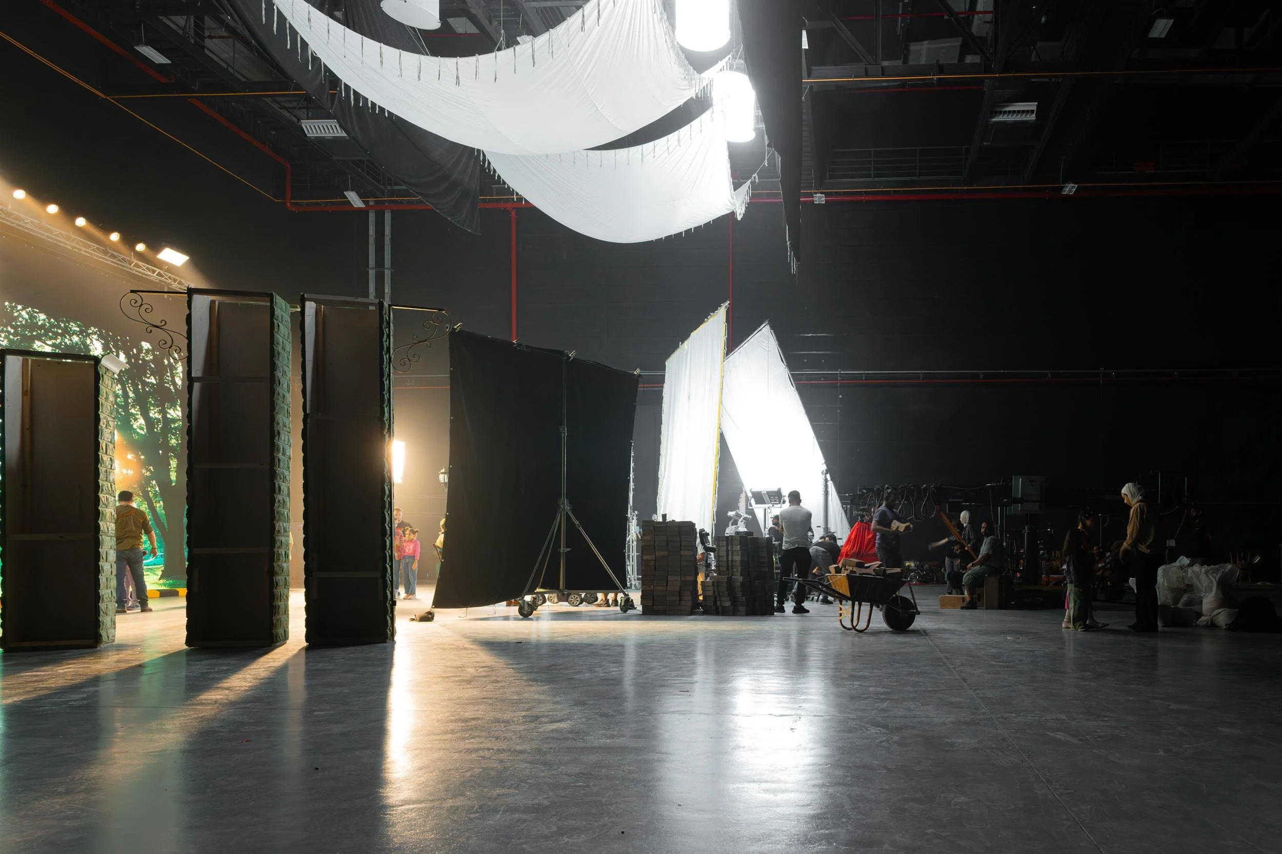 Ahlan Simsim unit still: Crew members work among large light diffusers and set pieces in a vast studio.