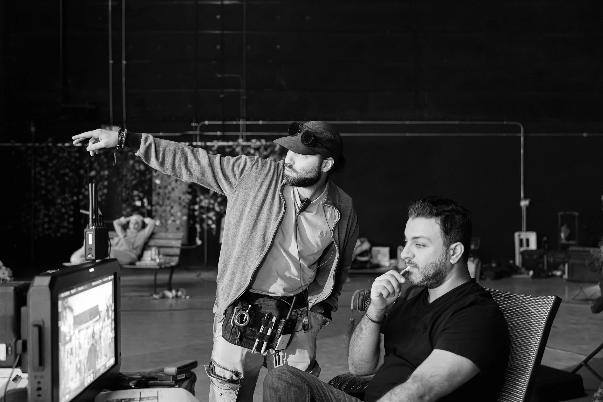 Ahlan Simsim unit still: two crew members look toward a production monitor while one points off-camera.