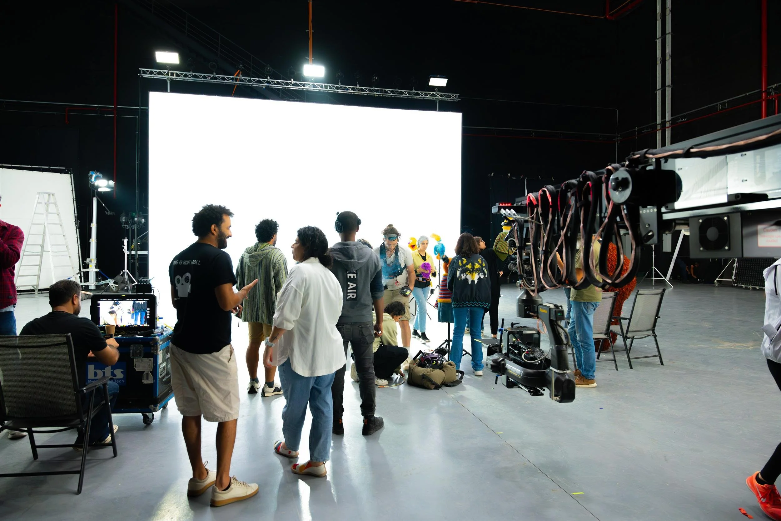 Ahlan Simsim unit still: crew gather before a bright white screen with a camera crane and Muppets nearby.
