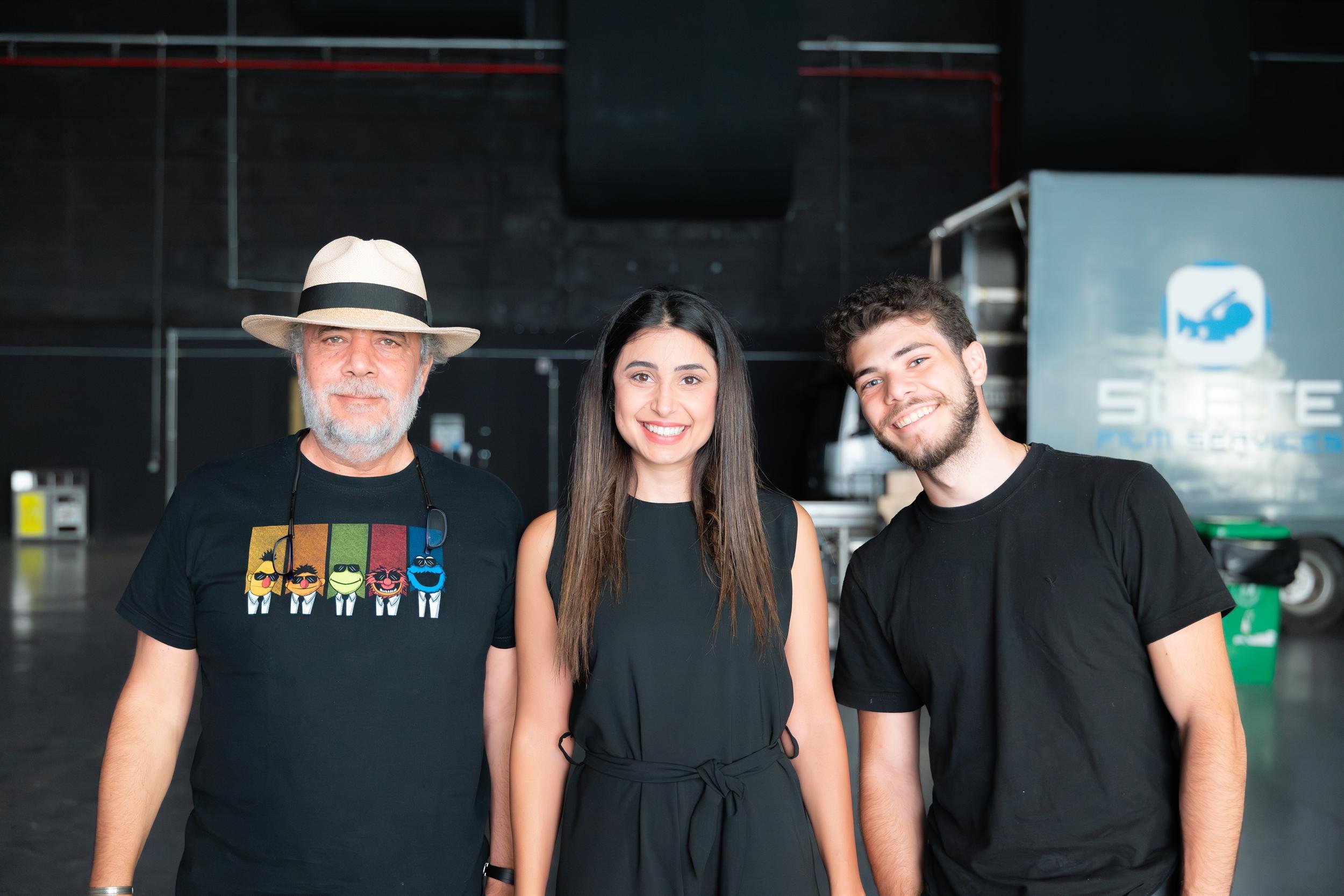 Ahlan Simsim unit still: three crew members pose together in a dark studio near a Slate Film Services truck.