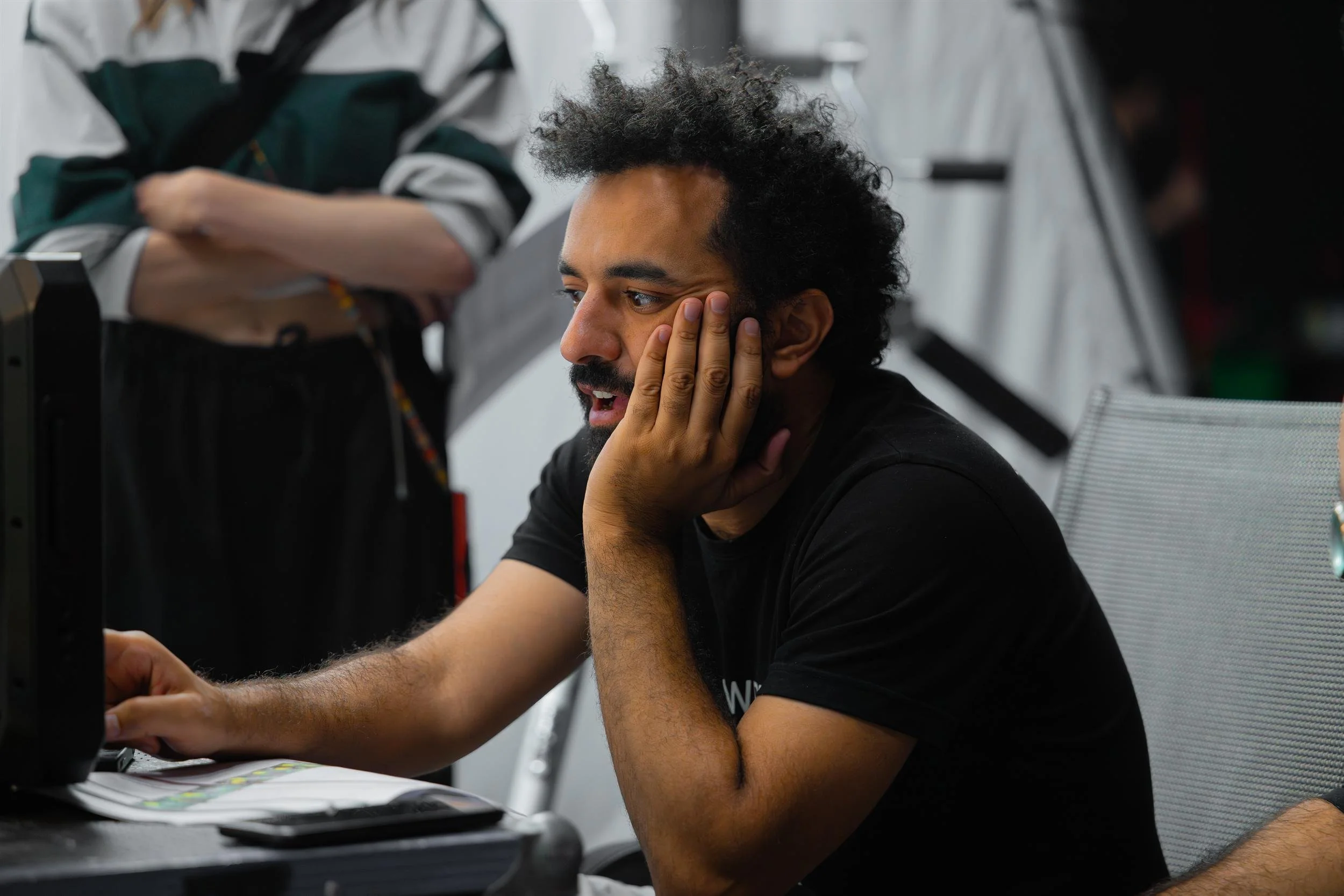 Ahlan Simsim unit still: A bearded crew member watches a monitor with his hand on his cheek on set.