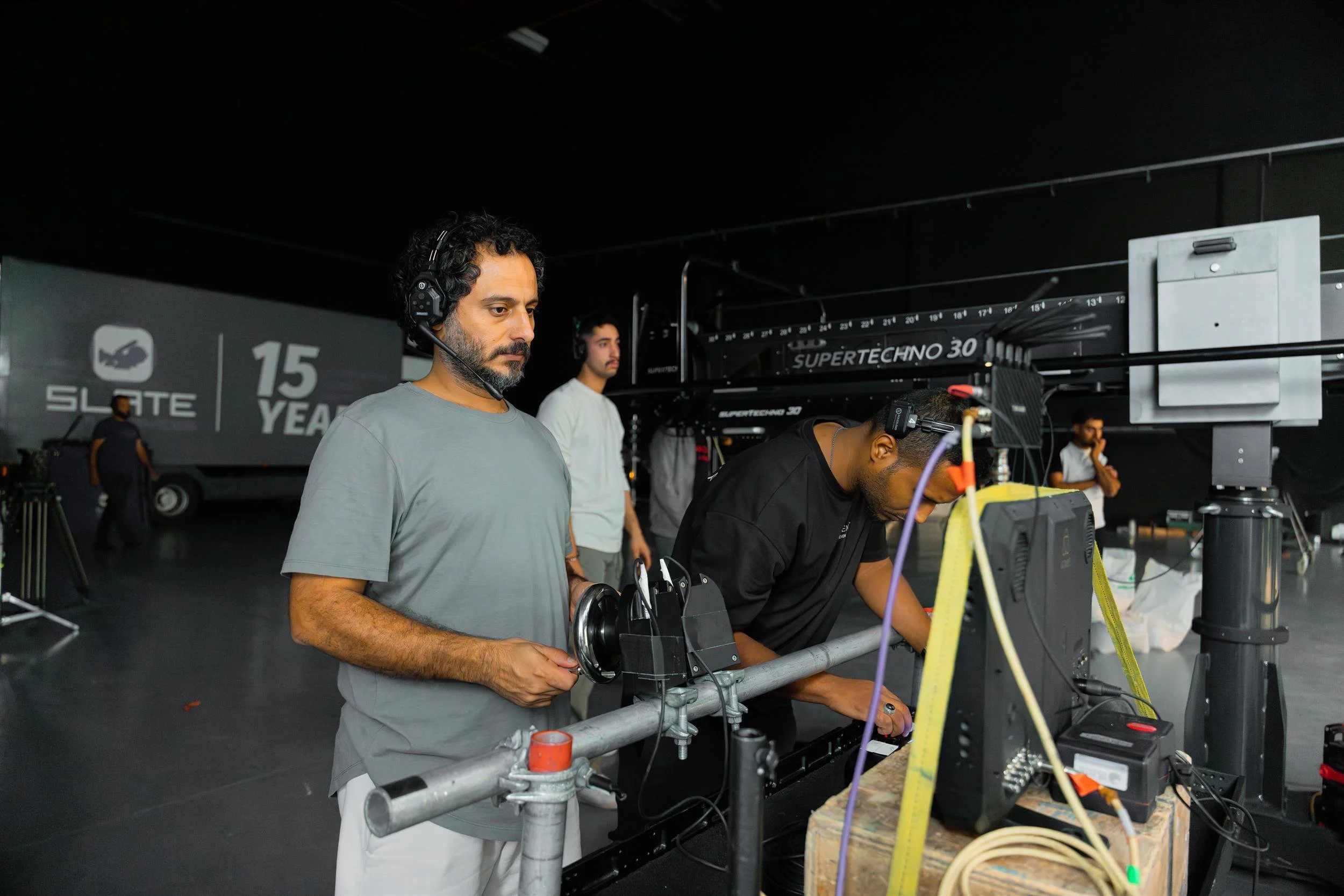 Ahlan Simsim unit still: Crew members work around a camera crane and monitors in a dark studio.