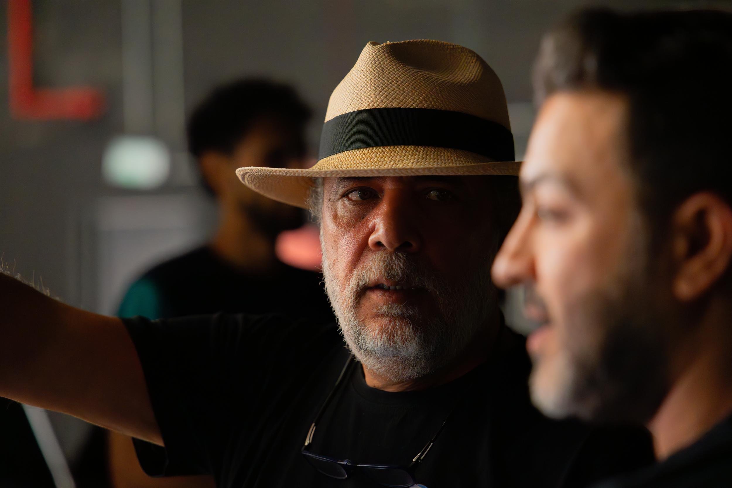 Ahlan Simsim unit still: A crew member in a tan fedora looks toward a monitor on a dark studio set.