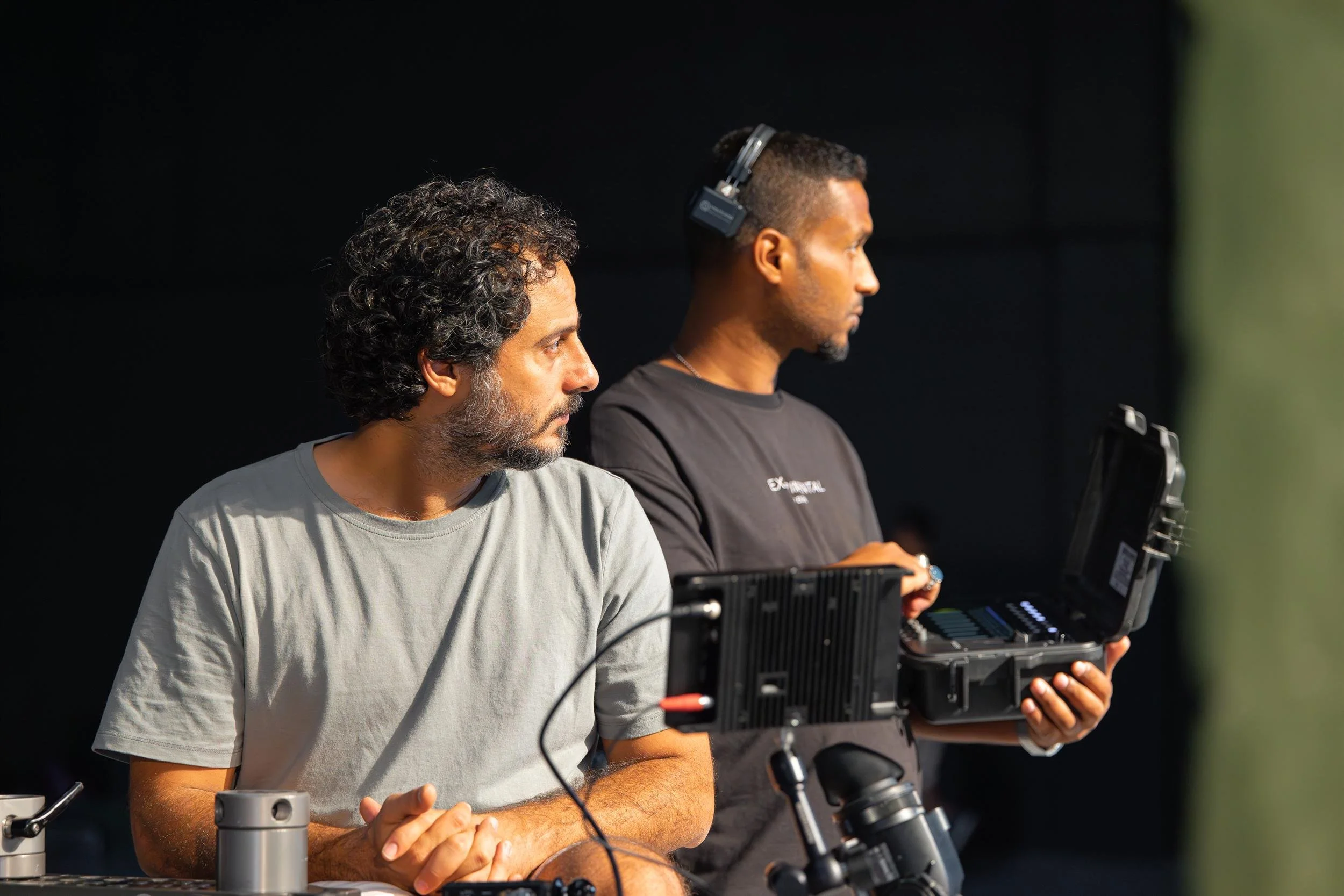 Ahlan Simsim unit still: Two crew members look off-camera while operating monitors and equipment on set.