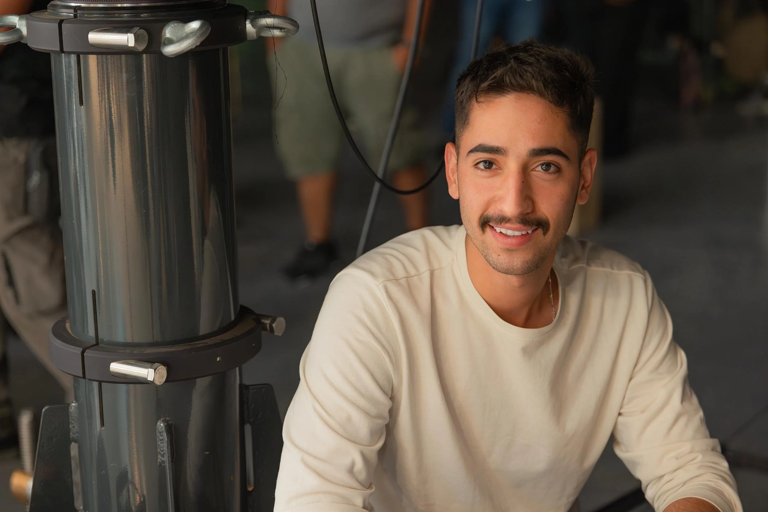 Ahlan Simsim unit still: A smiling crew member with a mustache poses in a studio next to production equipment.