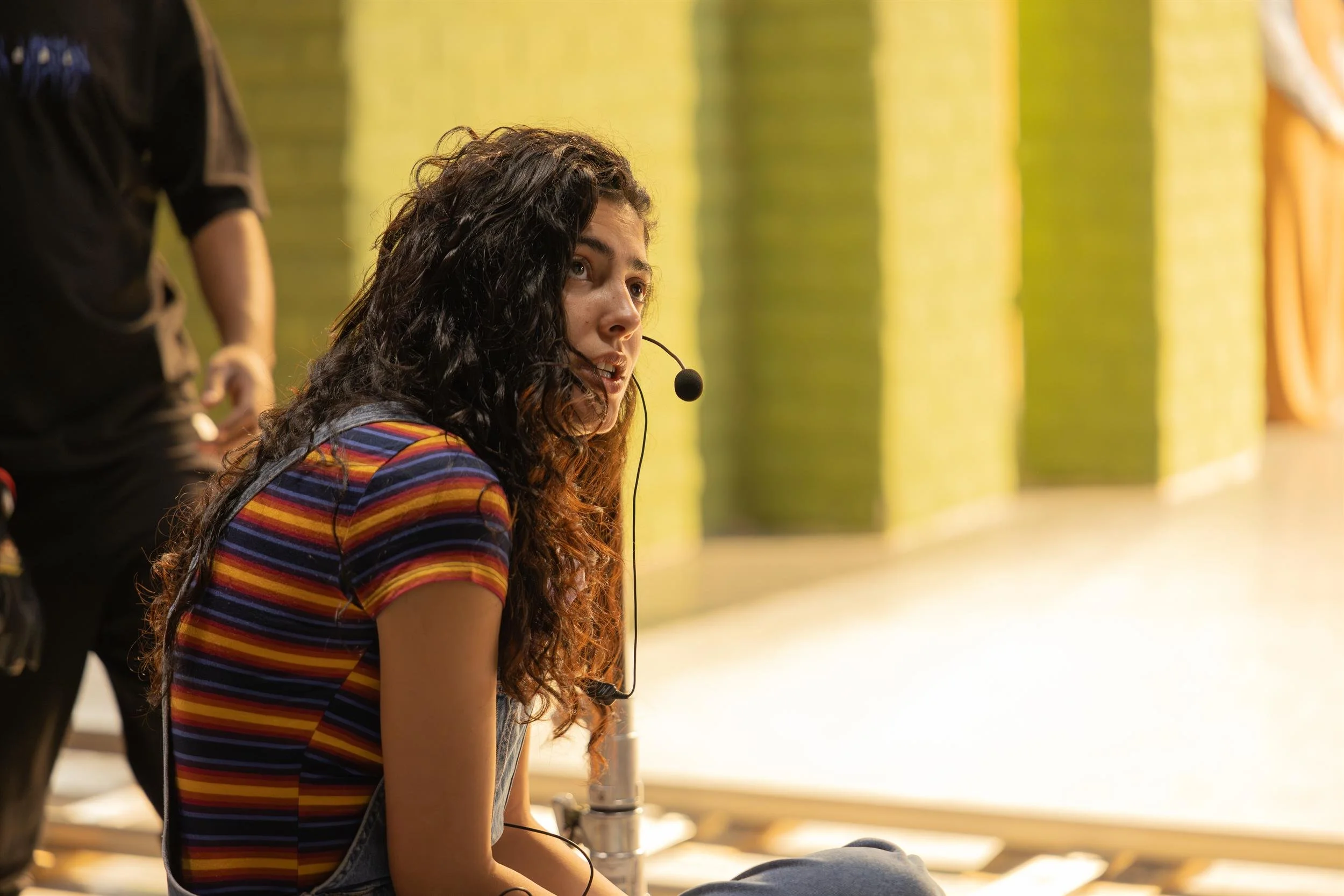 Ahlan Simsim unit still: A crew member in a headset and striped shirt looks off-camera on set.