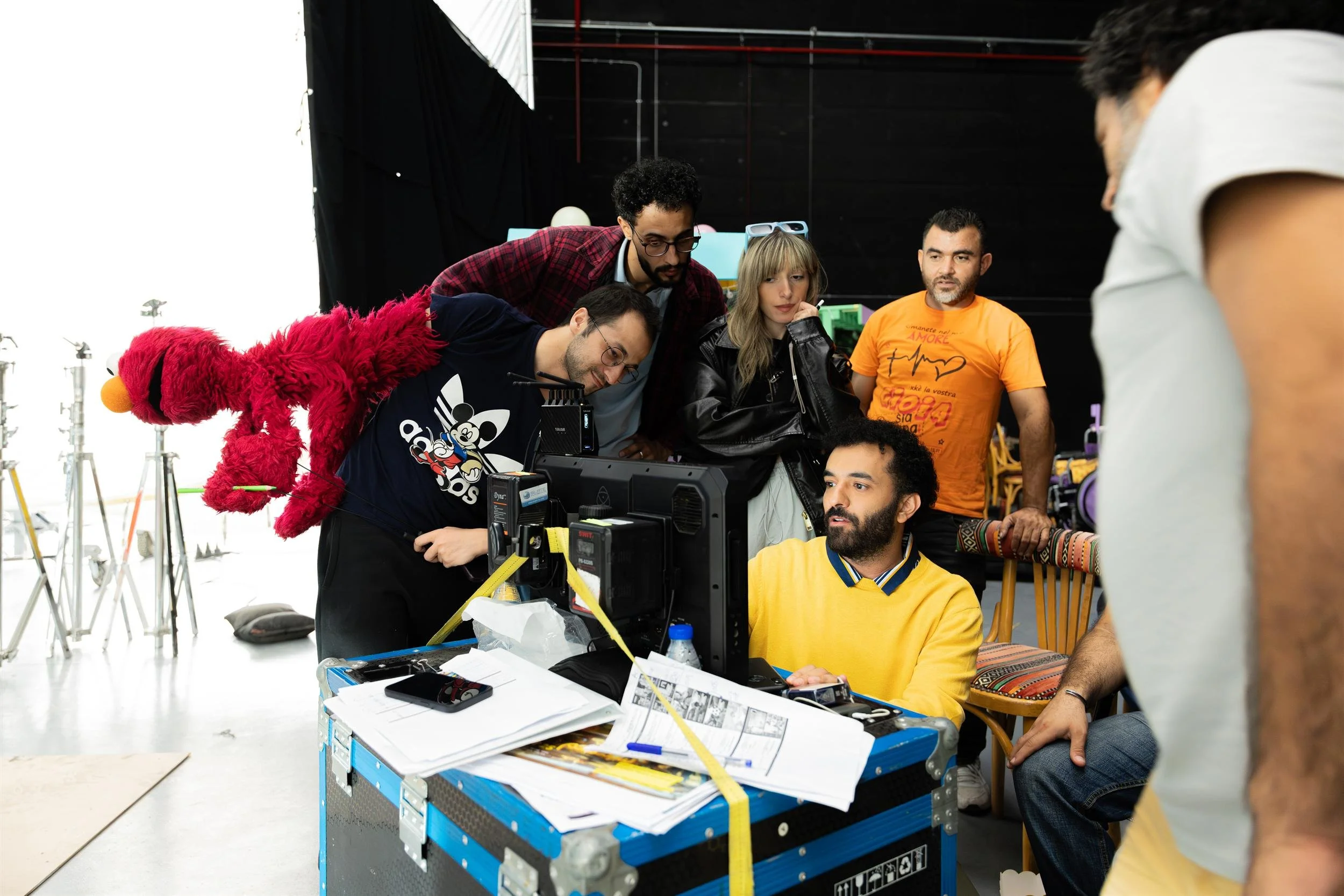 Ahlan Simsim unit still: crew and Elmo watch a production monitor on a strapped equipment case.