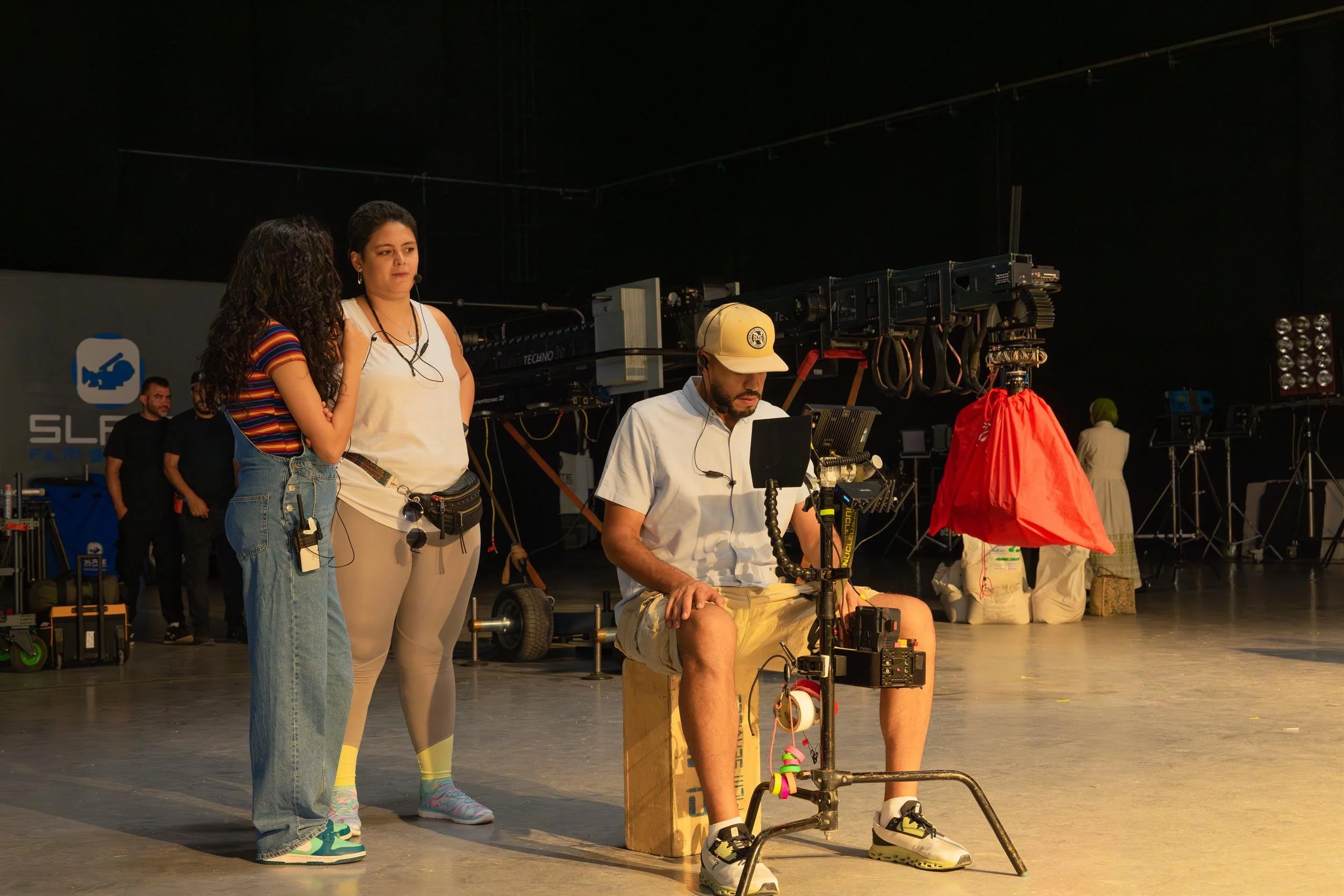 Ahlan Simsim unit still: Production crew members work with camera equipment and monitors in a large studio.