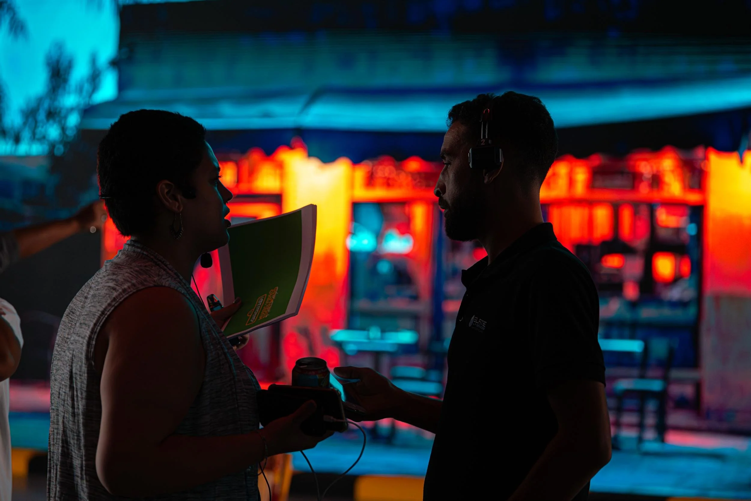 Ahlan Simsim unit still: two crew members talk in silhouette against a colorful night street set.