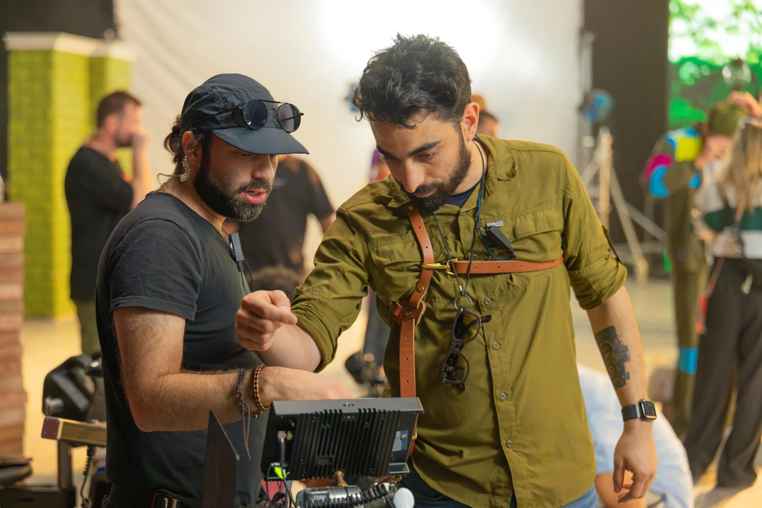 Ahlan Simsim unit still: Two crew members review footage on a field monitor on a brightly lit studio set.