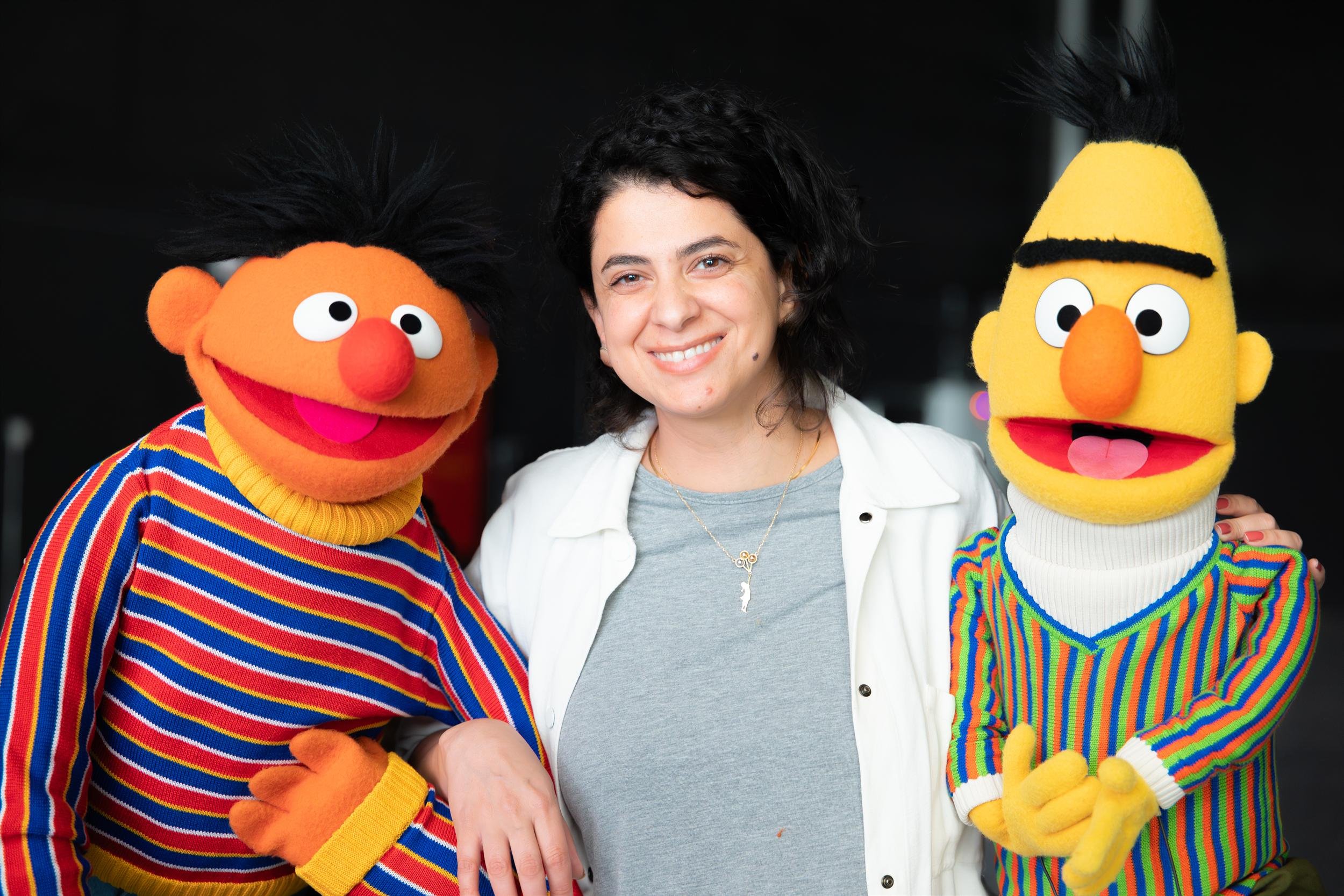 Ahlan Simsim unit still: a woman smiles while posing with Ernie and Bert.