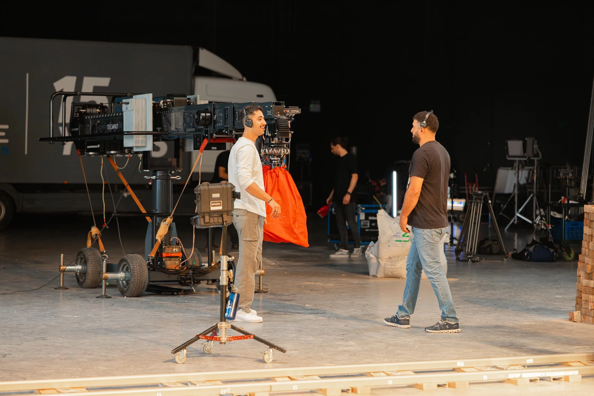 Ahlan Simsim unit still: Two crew members wearing headsets stand in a production studio near a large camera crane.