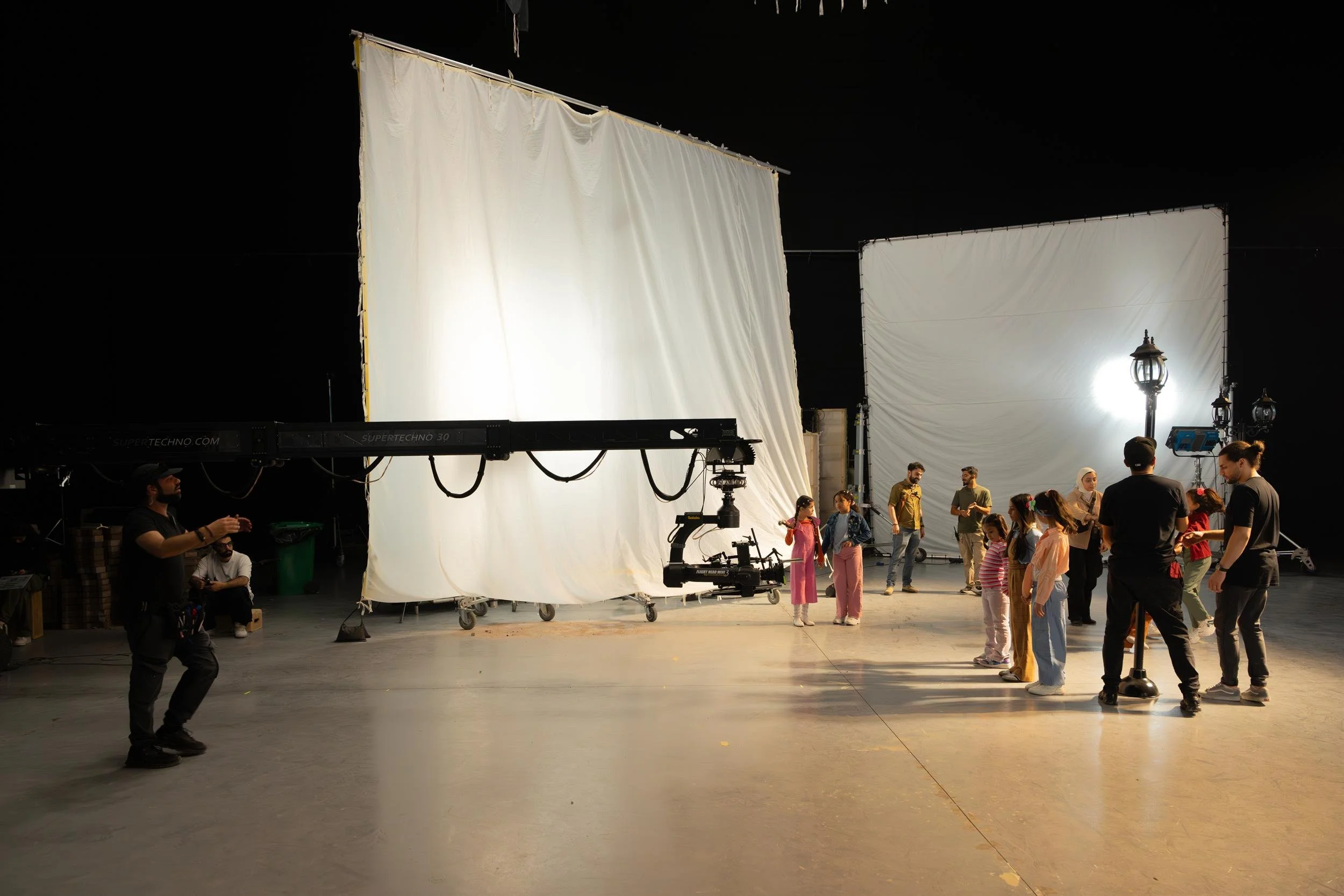 Ahlan Simsim unit still: a SuperTechno 30 camera crane beside children and crew under large lighting silks.