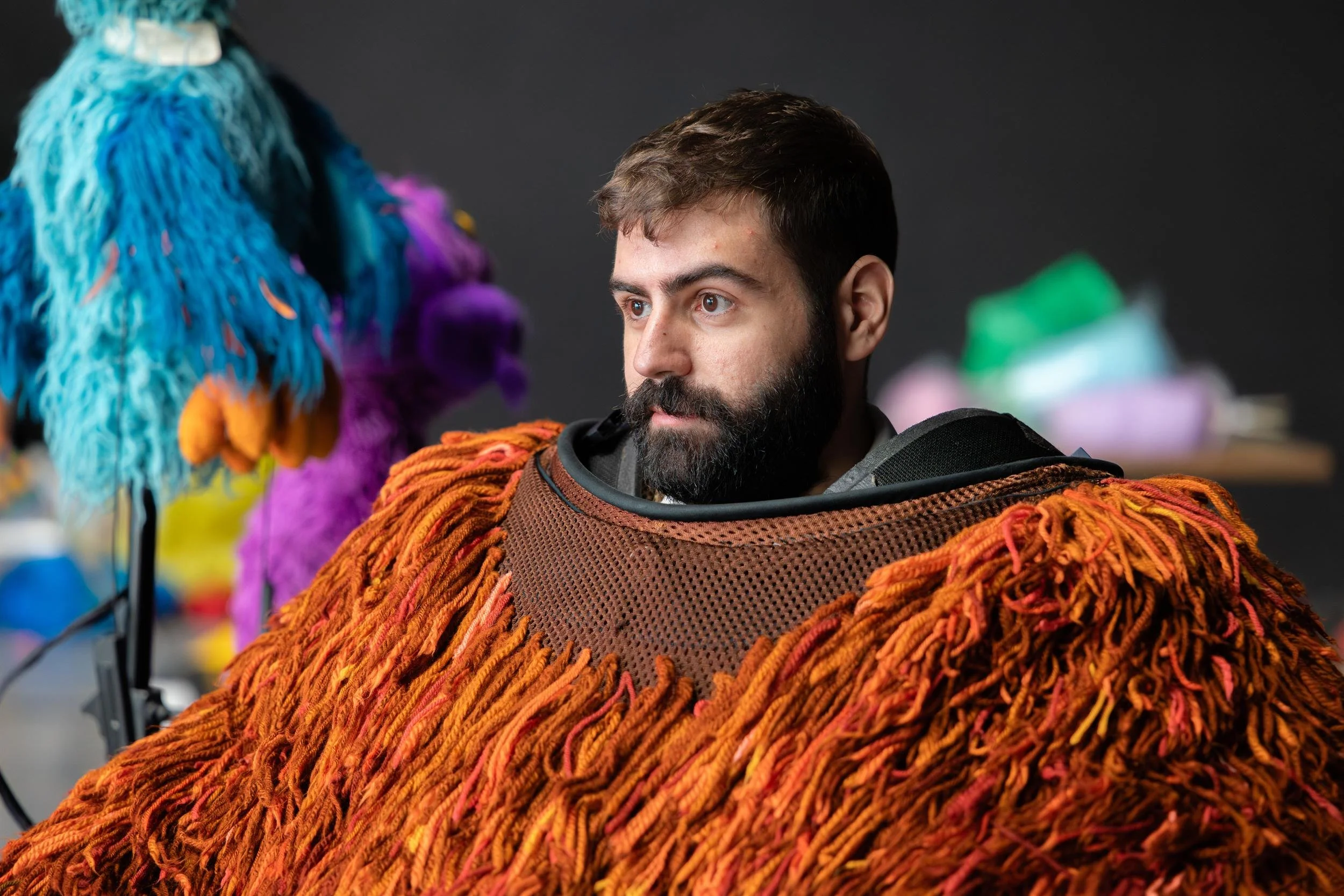 Ahlan Simsim unit still: a puppeteer wears the shaggy orange-brown torso of a large Muppet costume.