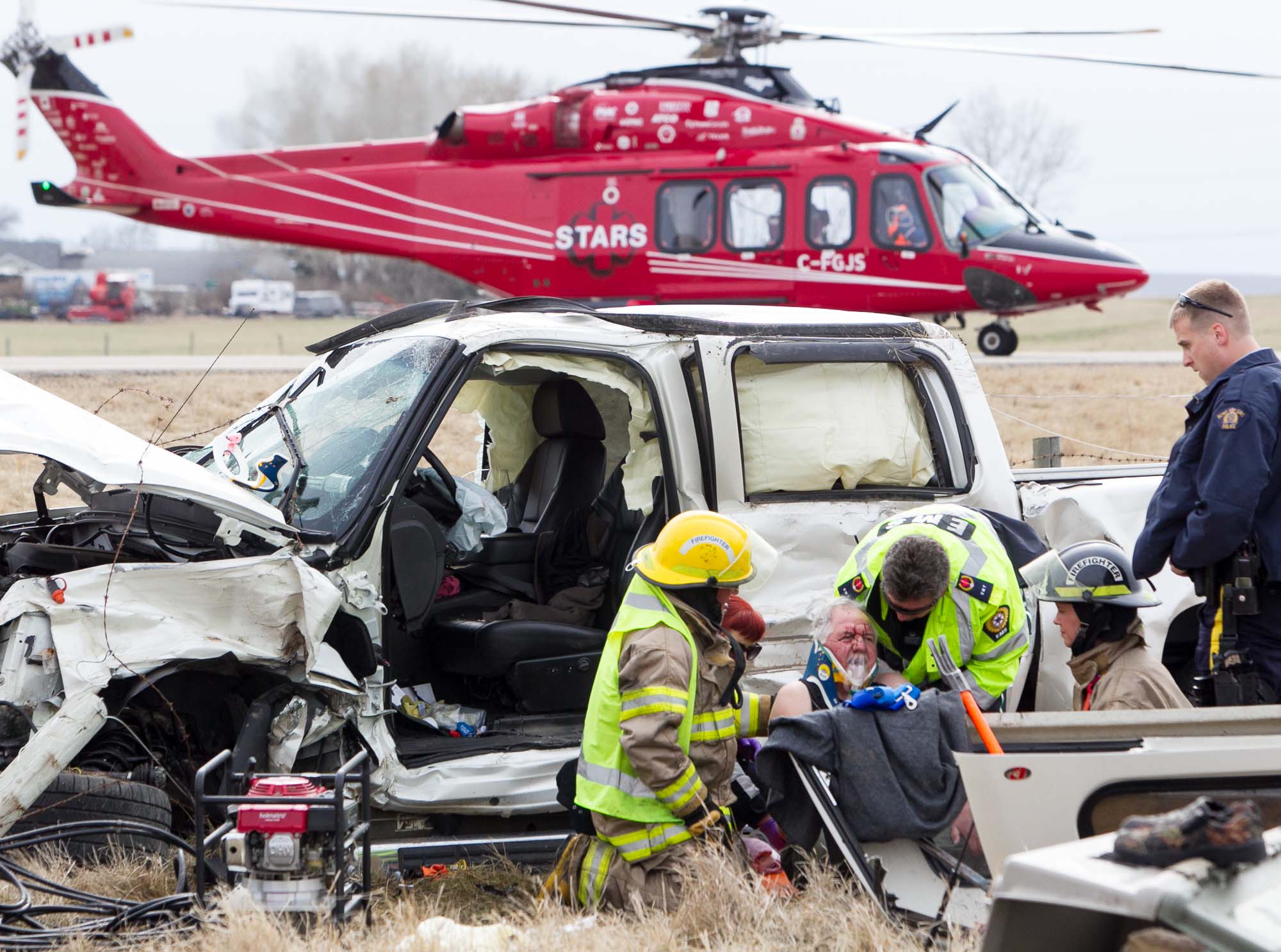 Firefighters and EMS workers tend to the driver of a vehicle involved in a two-vehicle motor vehicle collision at the intersection of Highway 580 and Rge. Rd. 25 in Mountain View County, Alta. on May 9, 2014. One of the drivers (shown) was transported to hospital via STARS air ambulance and the other was transported via ground ambulance.