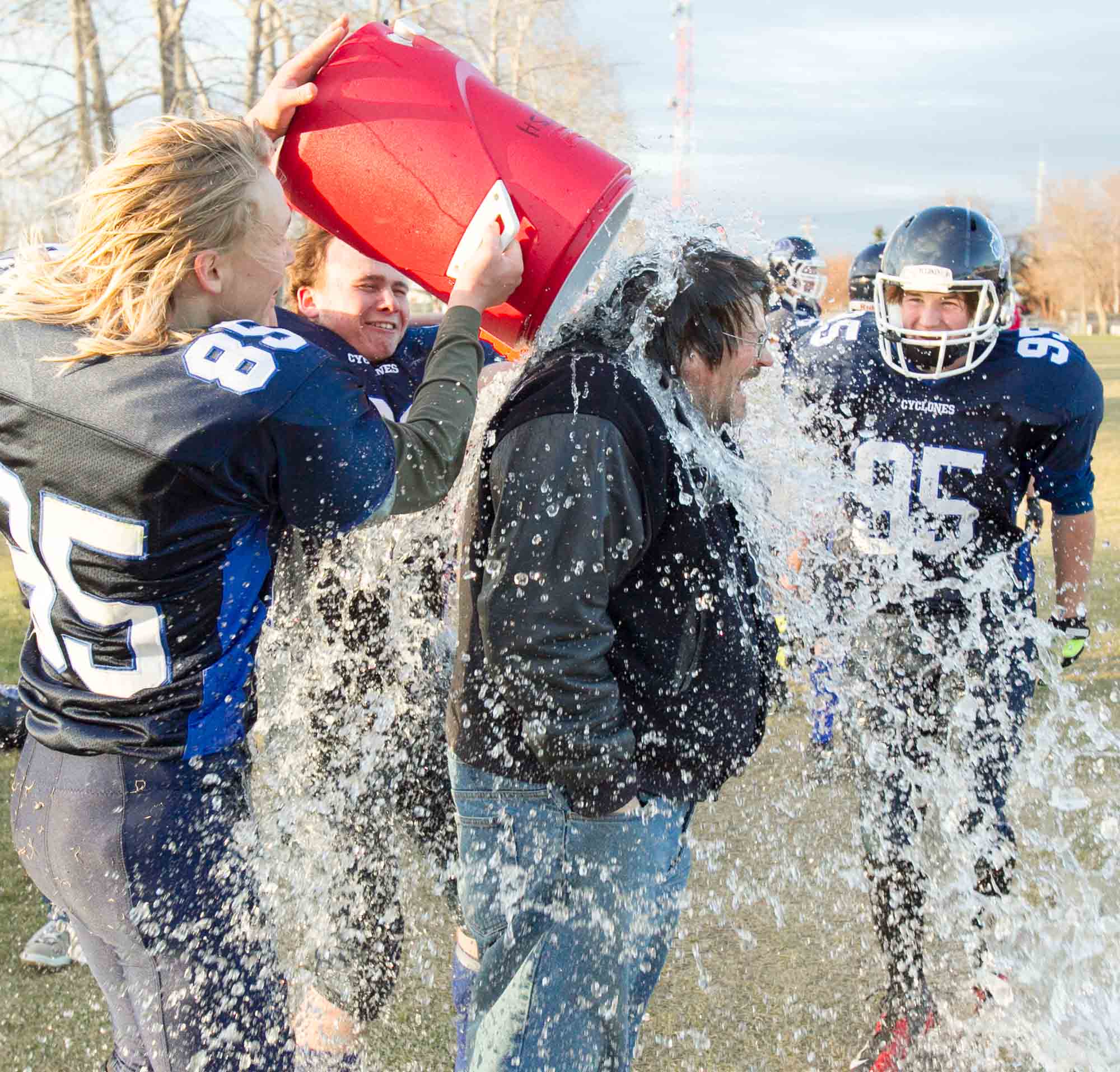 Innisfail Cyclones players Simon Biggar, left, and Kelsey Katchuck douse coach Trevor Wooff with water while Darian Davis, right, looks on at the end of their championship game at Innisfail High School in Innisfail, Alta. on Oct. 25, 2014. The Cyclones defeated Sundre Bison 64 to 27.