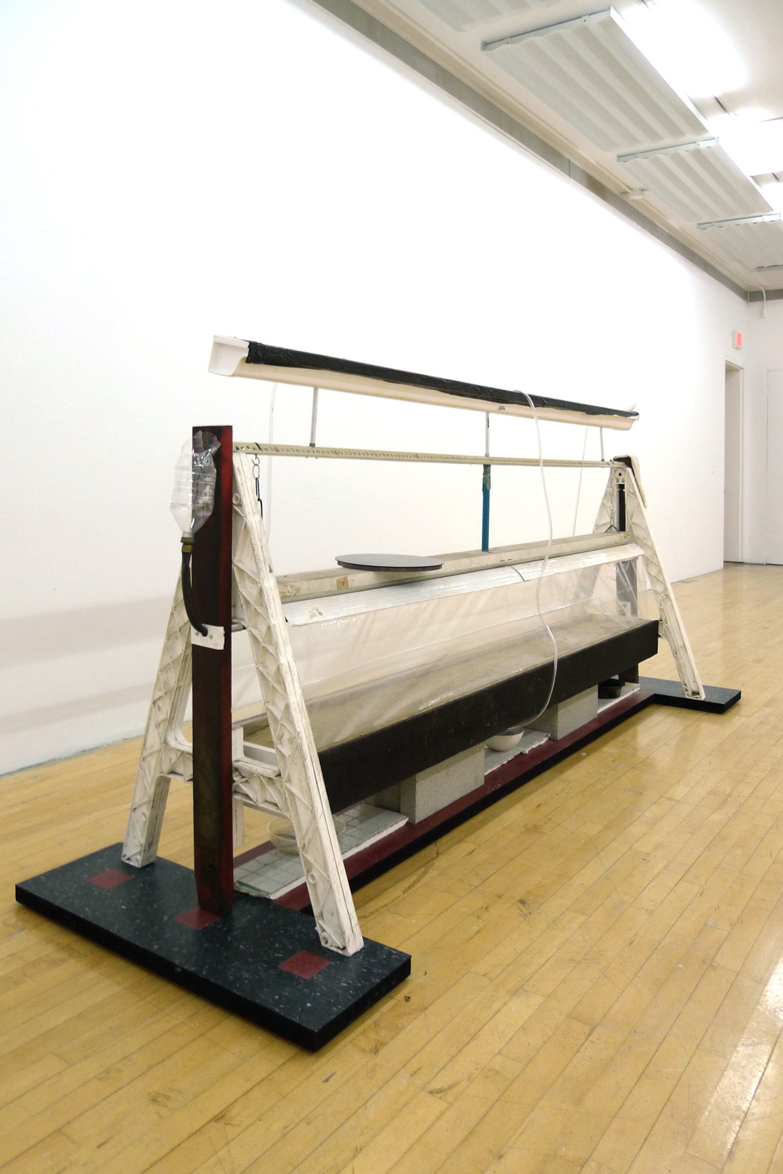  Jonathan Mildenberg  A Song of Ascents , 2018 wood, steel, rubber floor tile, Plasticade barricade A-frames, commercial steel shelving brackets, PVC vinyl tubing,  gravel, sand, plastic tarp, Velcro, Florescent lighting fixture, chain, zip ties, alu