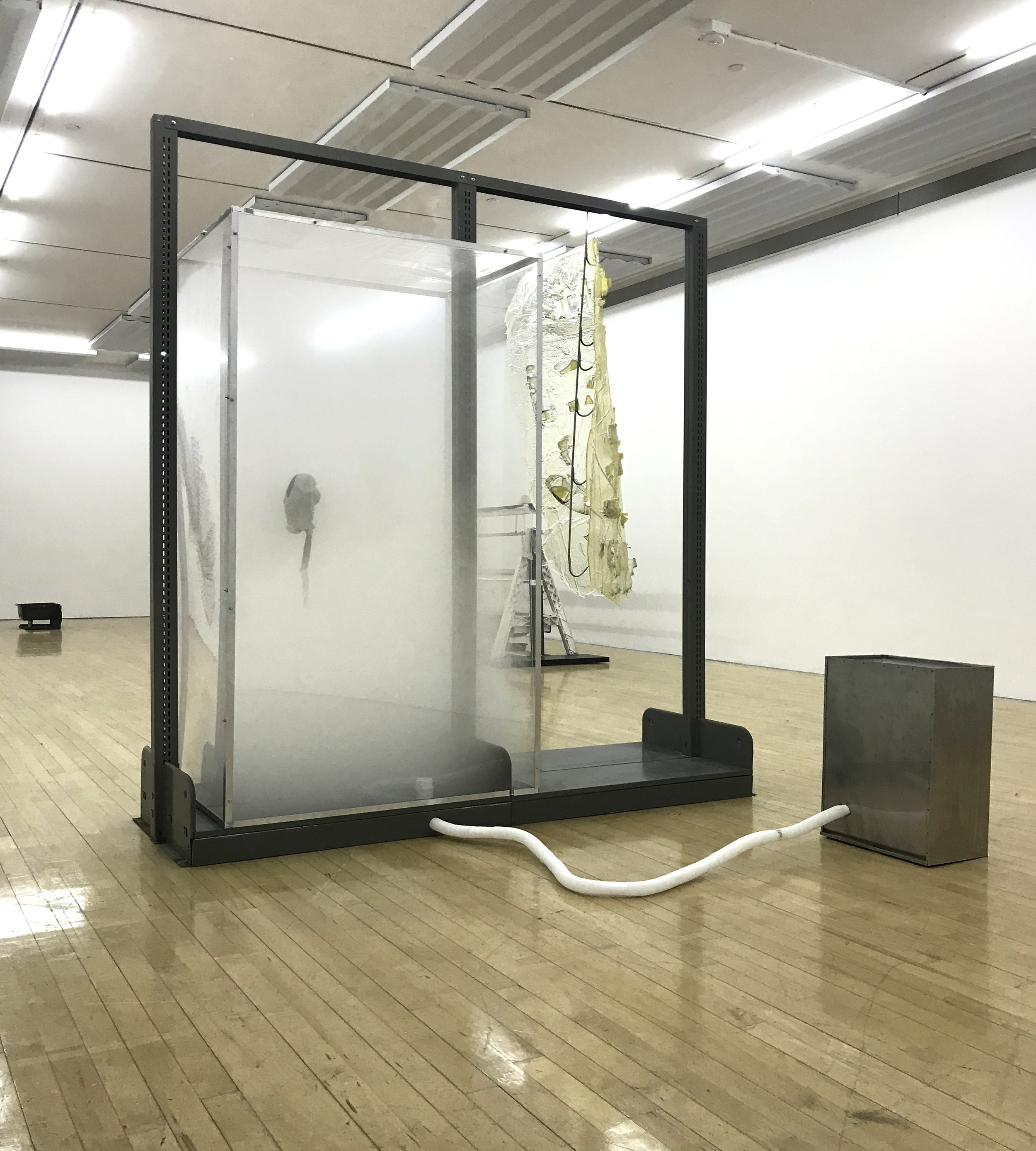  Vladislav Markov  Untitled , 2018 library shelves, Plexiglas, polyurethane engine cast, gas mask, fog machine,  plastic hose, self-adhesive carpet protector film 84 x 84 x 24 inches (213 x 213 x 61 cm) (VM3) 