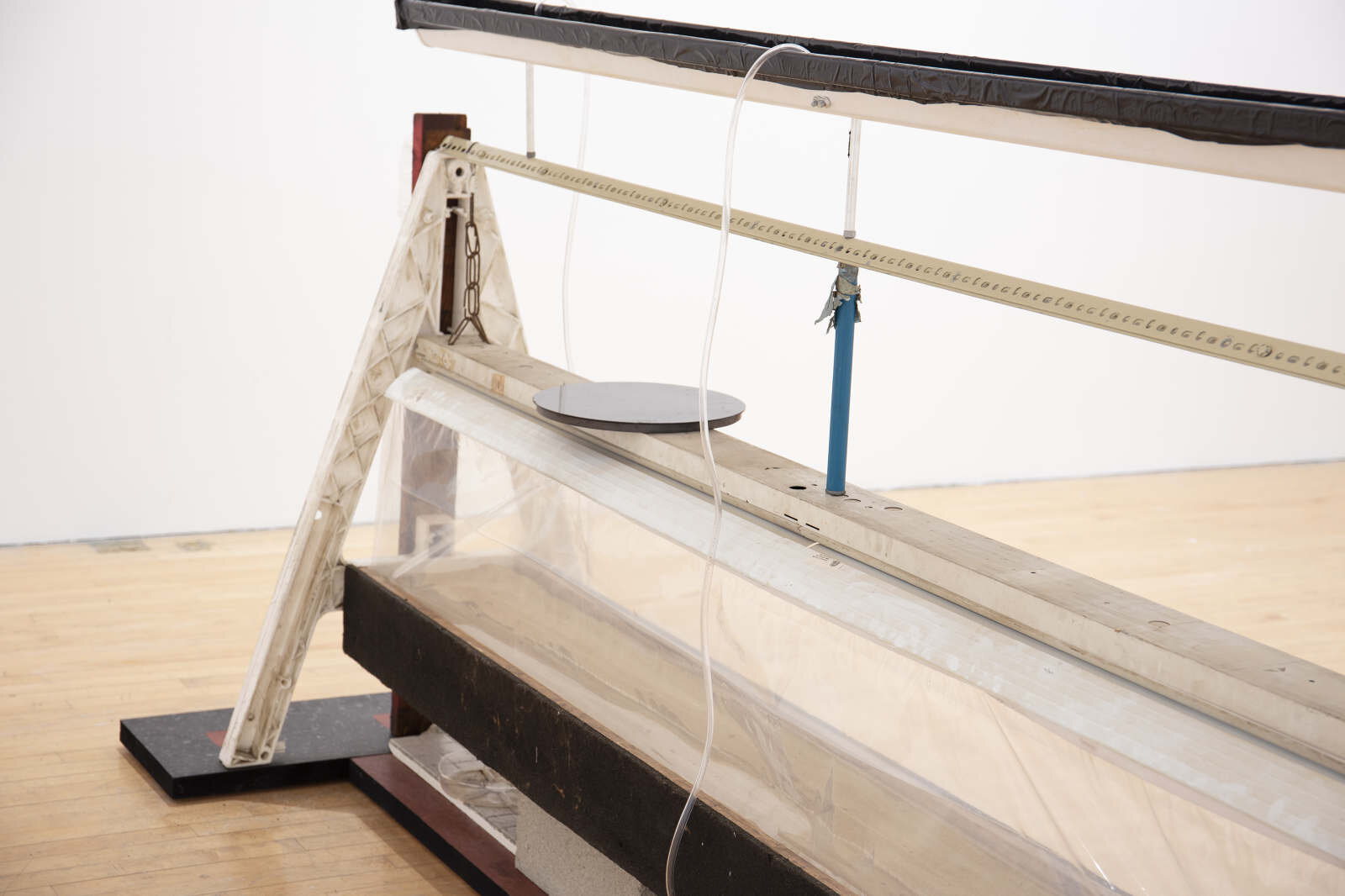  Jonathan Mildenberg  A Song of Ascents , 2018 wood, steel, rubber floor tile, Plasticade barricade A-frames, commercial steel shelving brackets, PVC vinyl tubing, gravel, sand, plastic tarp, Velcro, Florescent lighting fixture, chain, zip ties, alum