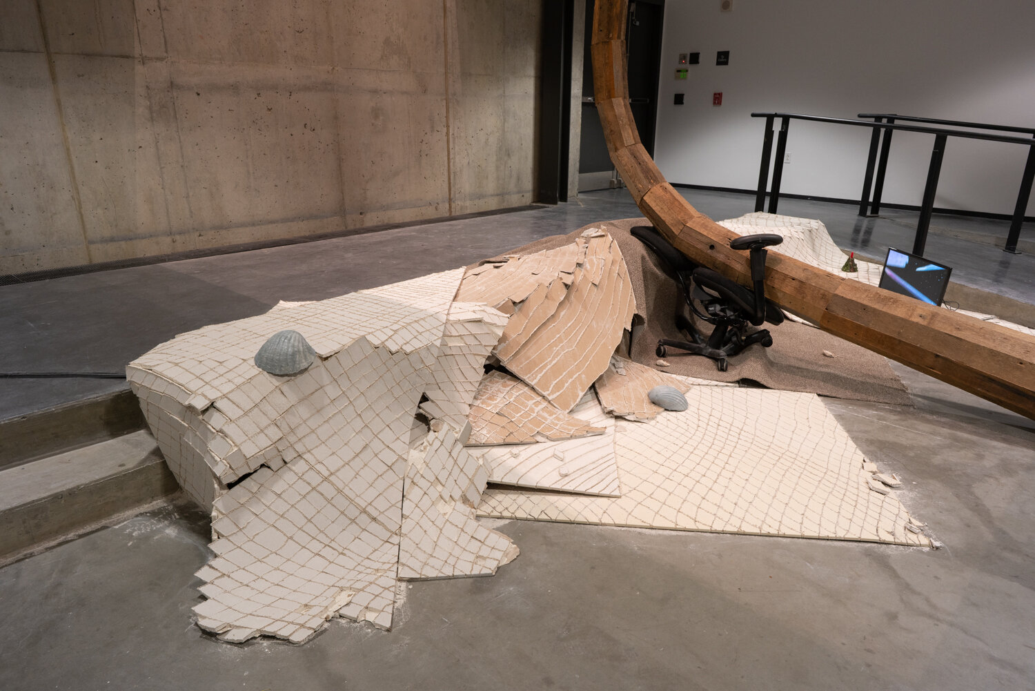  Alex Zak  Swamped , 2019 Sheet rock, plaster wrap, carpet, wood, steel, aluminum, paint, cement, sand, oven-bake clay,   office chair, modified ceiling fan, Monitor, Keyboard, aquarium volcano, red sharpie 192 x 204 x 196 inches (488 x 305 x 498 cm)
