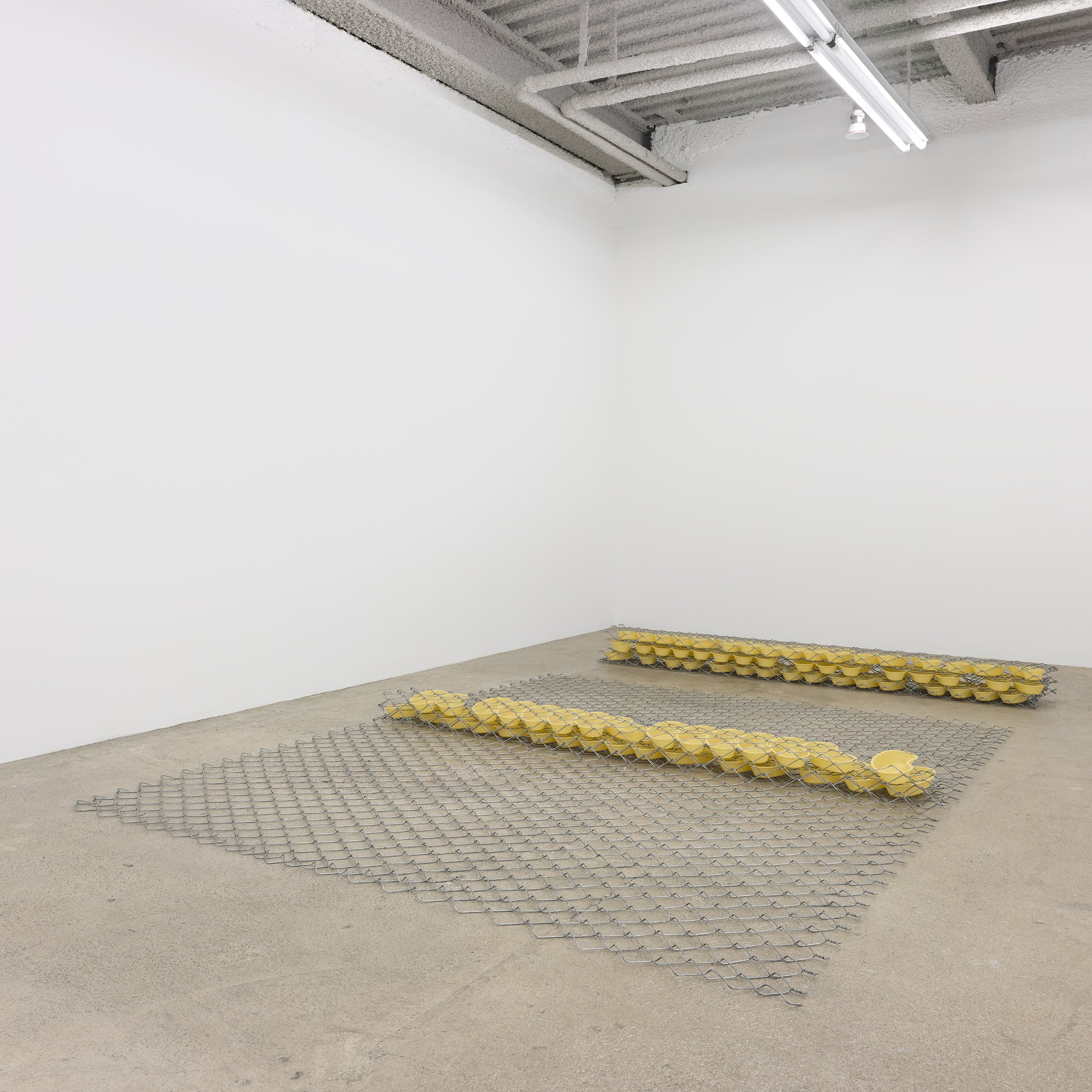  Bat-Ami Rivlin  Untitled (fence, bedpans) , 2021 chain link fencing, yellow kidney basins 8 x 120 x 72 inches (20 x 305 x 183 cm) Installation view M 2 3, New York, 2022 BR21 