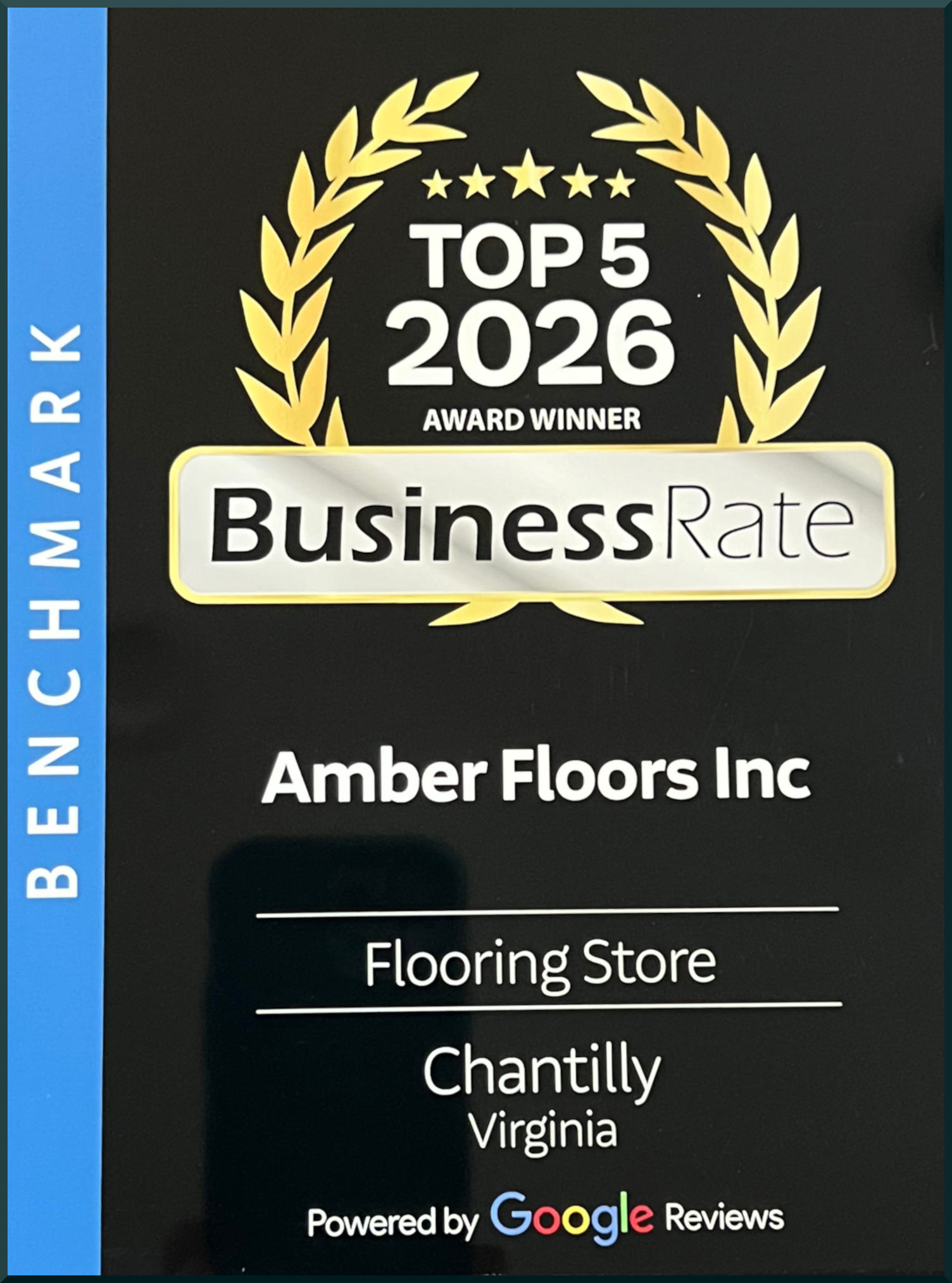 Award badge for Top 5 2026 Business Rate Winner by Amber Floors Inc, featuring a black background with a gold laurel wreath and stars, blue sidebar with text, and Google reviews.