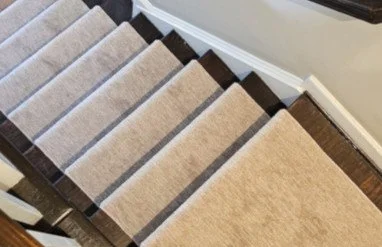 Multiple carpet samples stacked on top of each other in various shades of beige and brown.