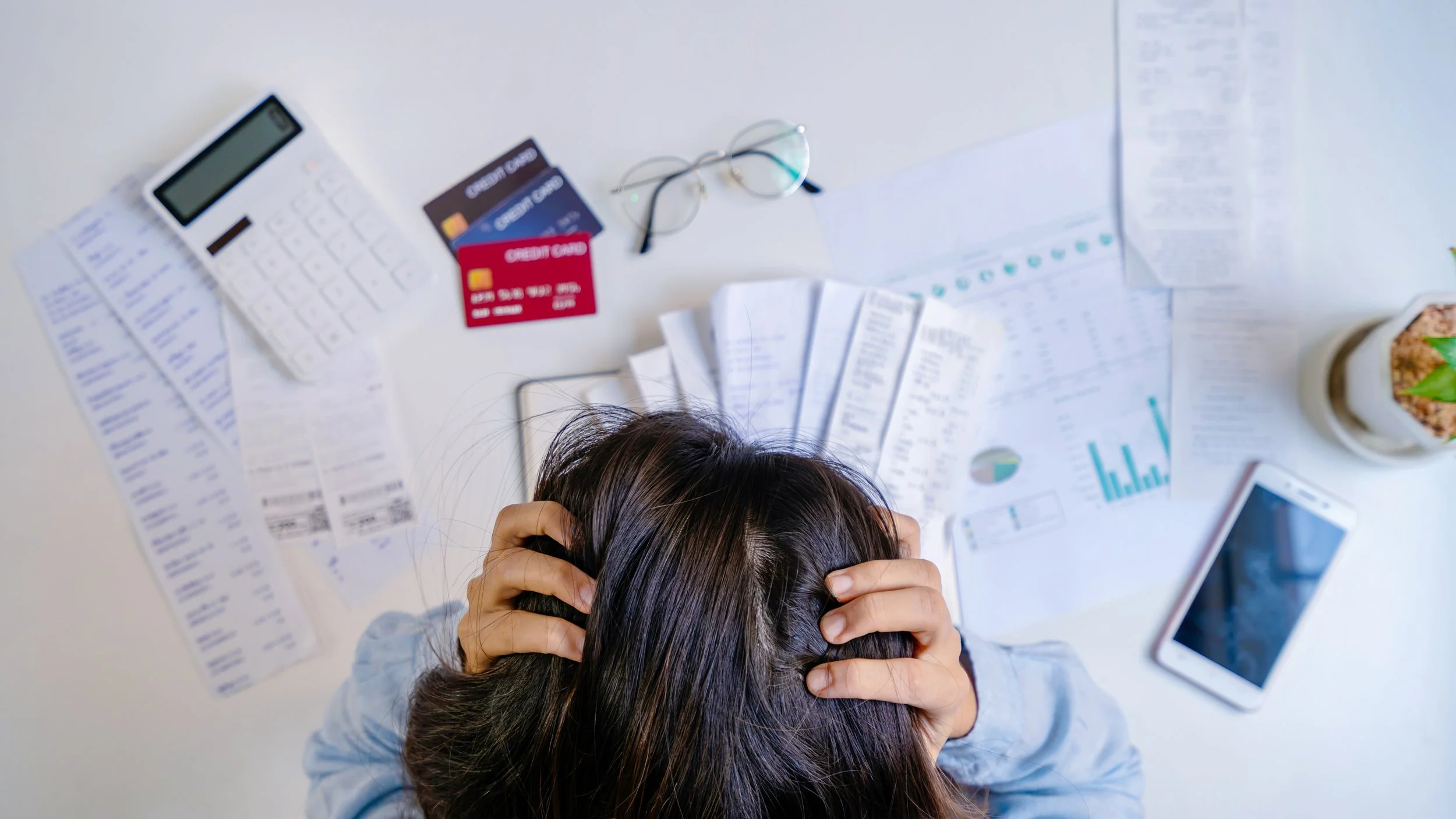 Overwhelmed small business owner surrounded by financial documents and receipts — bookkeeping help that gives NWA business owners peace of mind