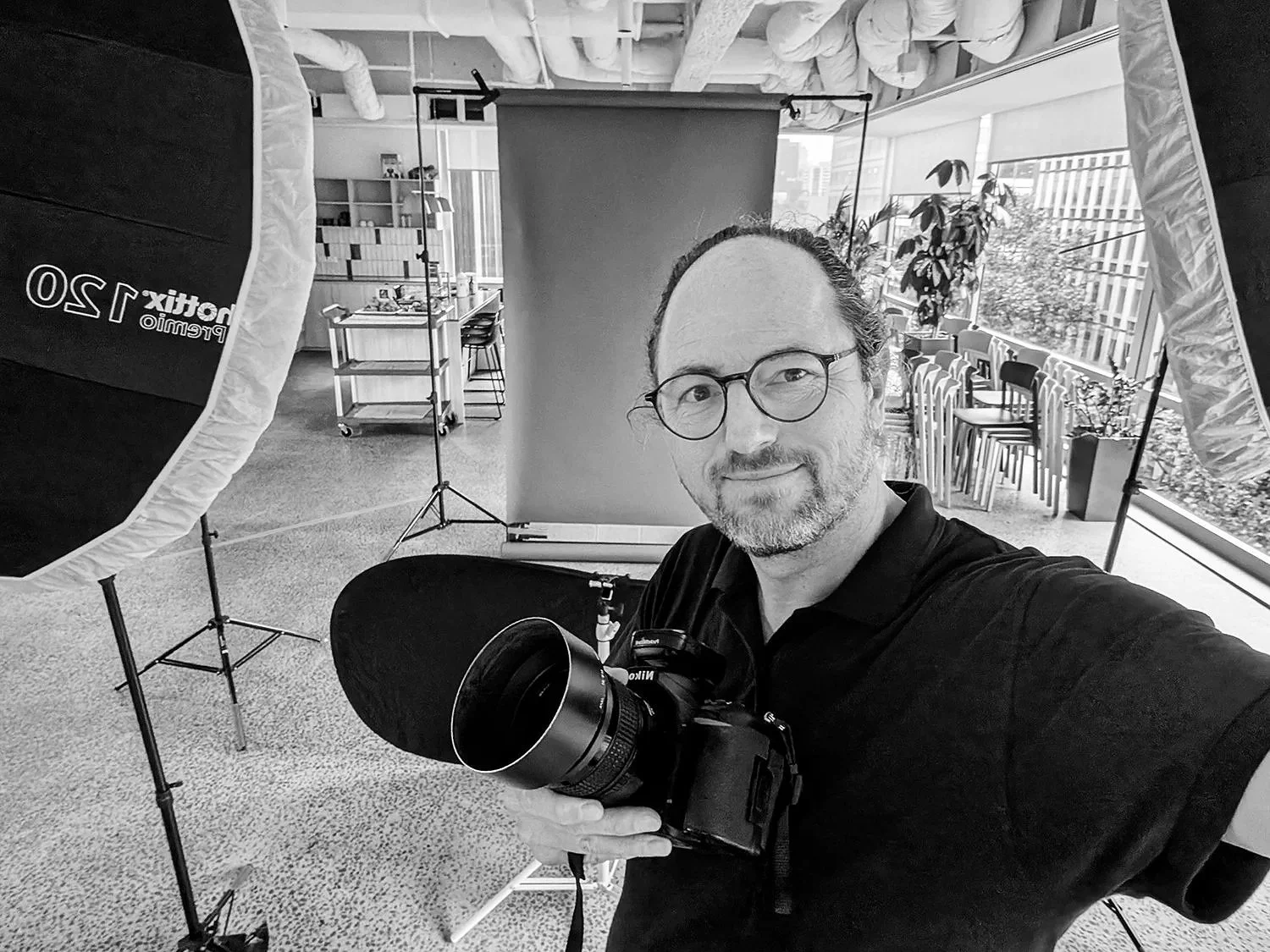 Melbourne professional photographer Hamish Appleby holding a Nikon camera in a studio lighting setup.