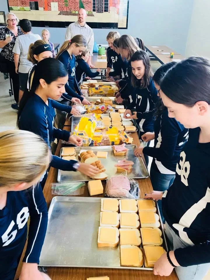 St. Timothy student-athletes work together with members of the St. Vincent dePaul society to make sandwiches for families at St. Lawrence Haven.