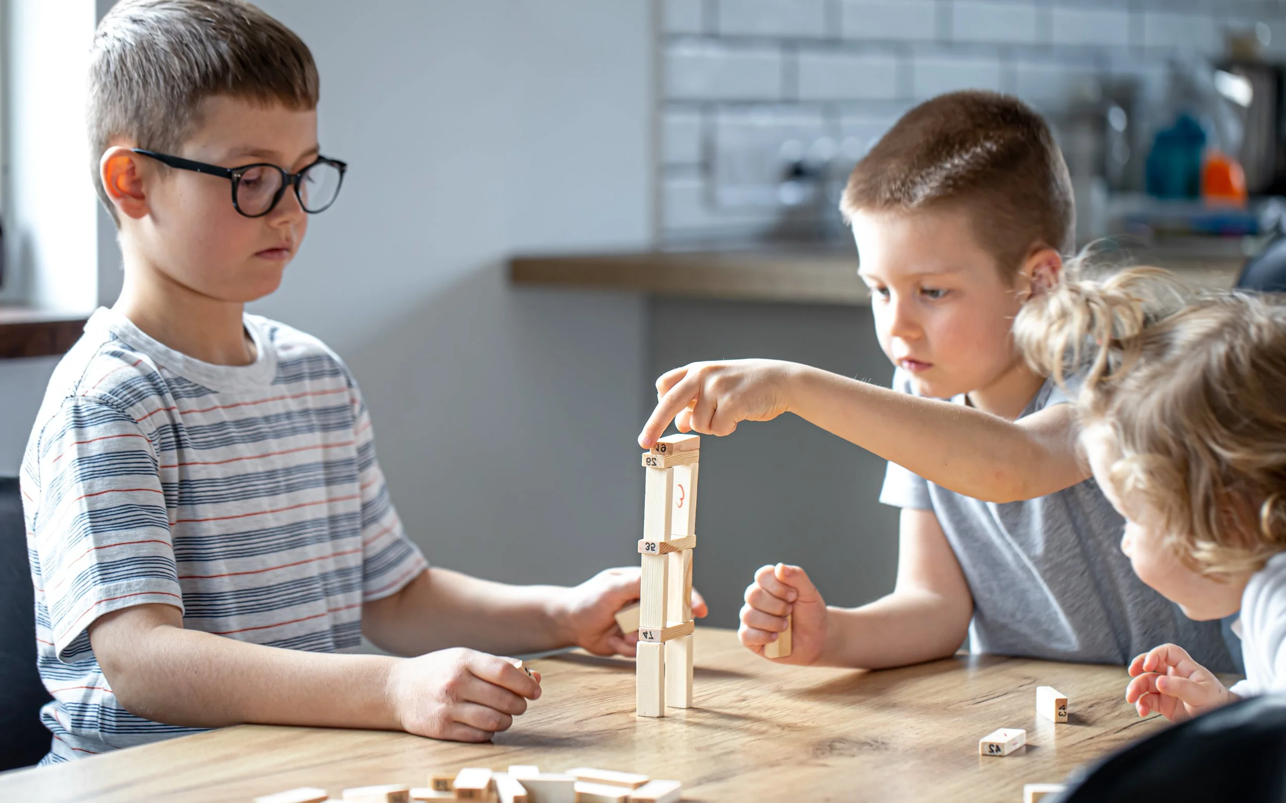 small-children-play-board-game-with-wooden-cubes-at-home-in-the-kitchen.jpg