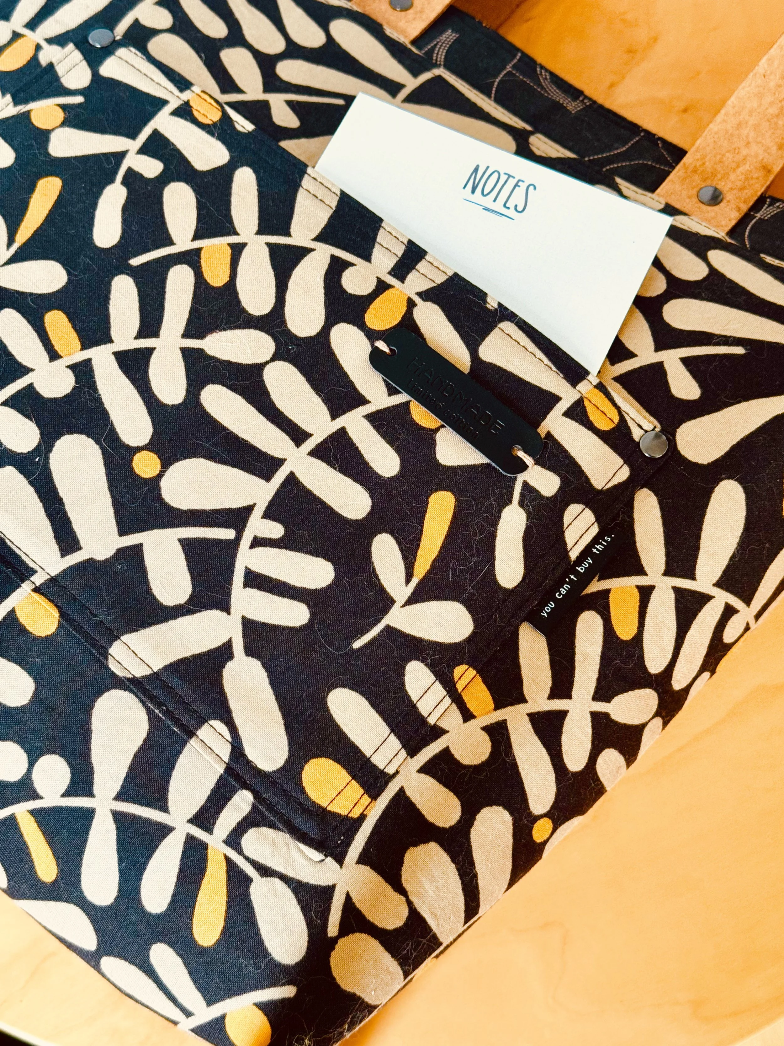 Close-up of the MIRA Sheridan Tote with a light card tucked into the outside pocket to reveal the hidden pocket edge.