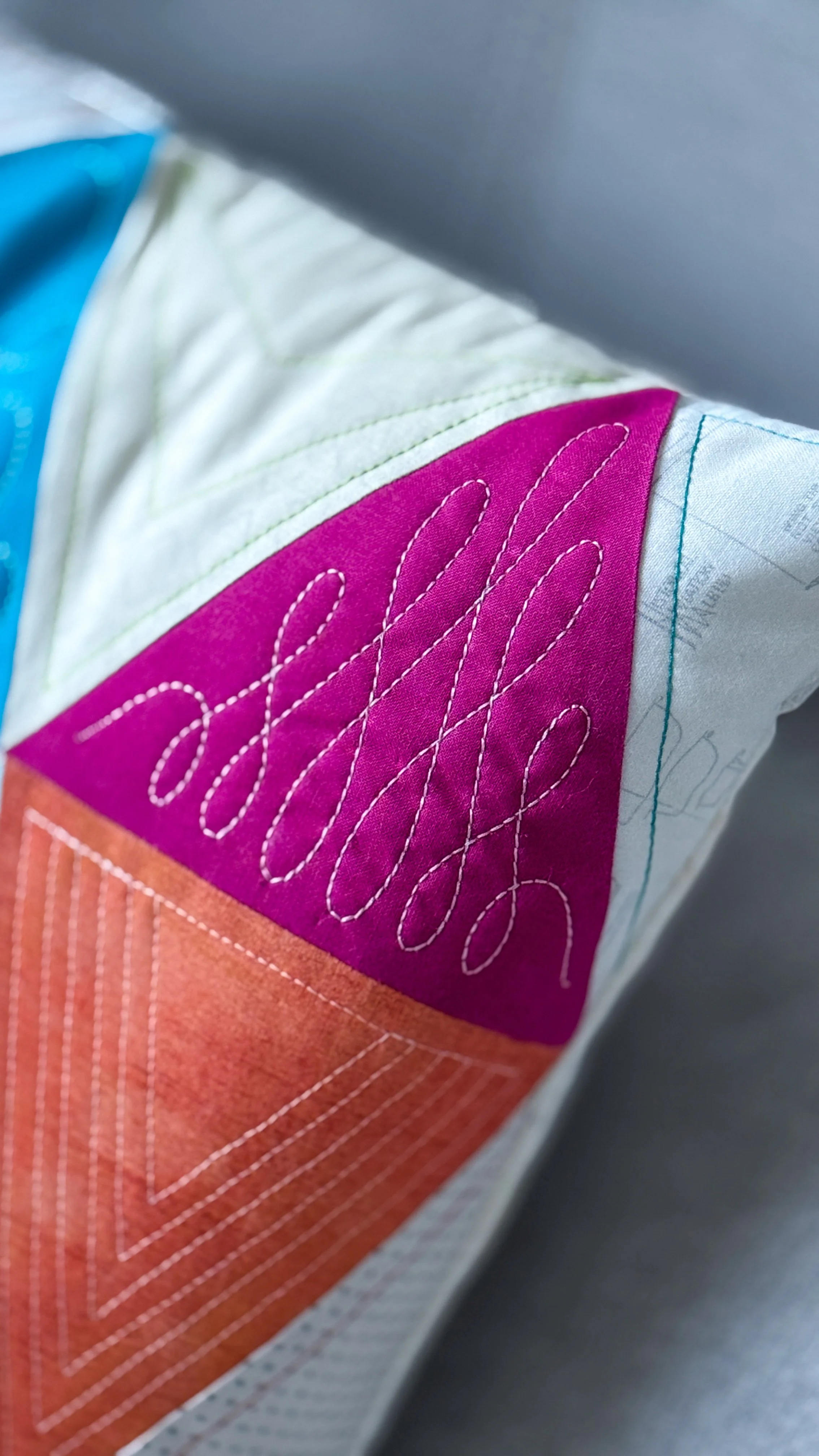 Detail view of precise quilting and decorative stitching on a colorful geometric pillow