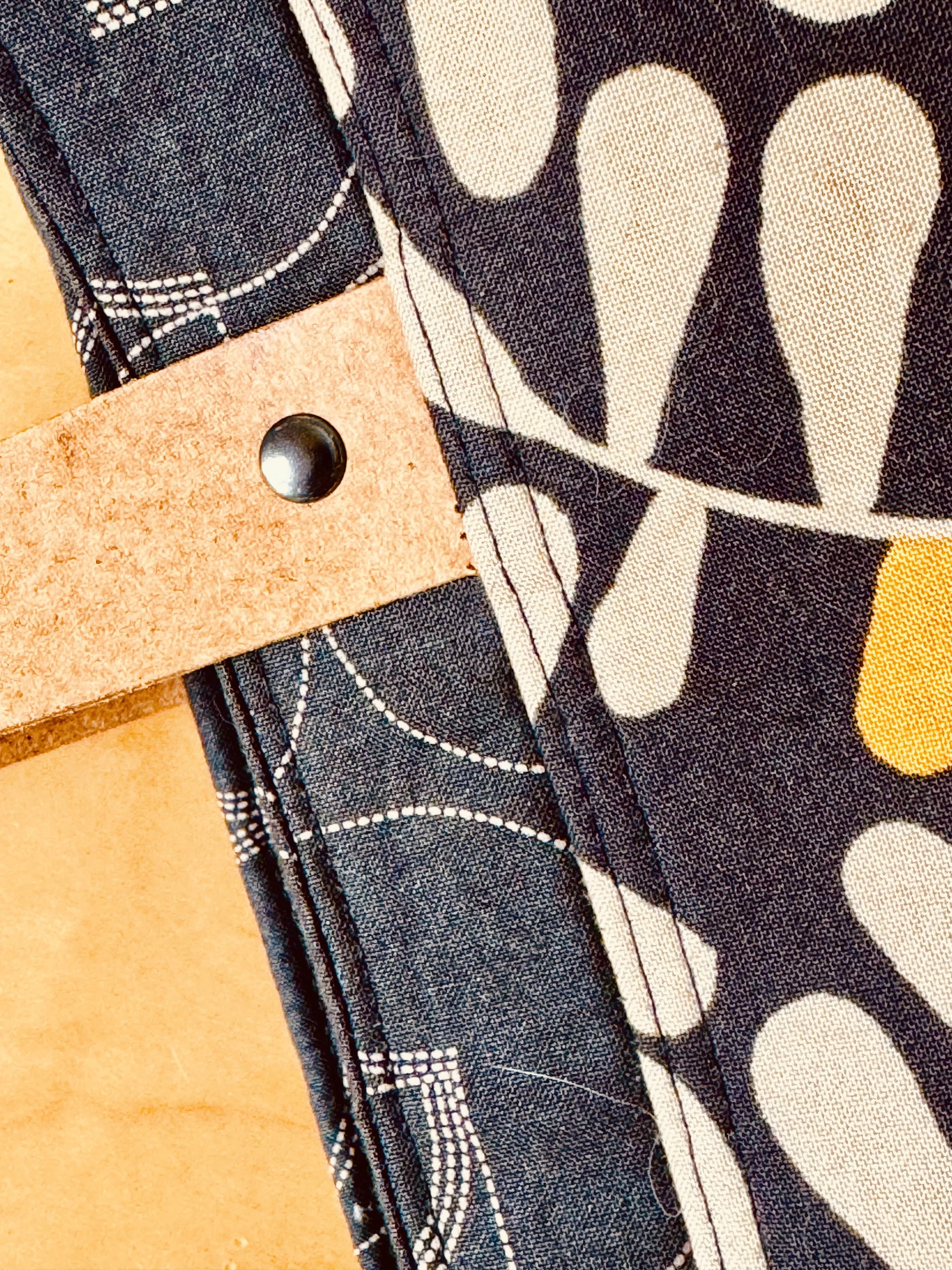 Detail view of the MIRA Sheridan Tote showing warm leather handles, hardware, quilting and golden fabric accents.