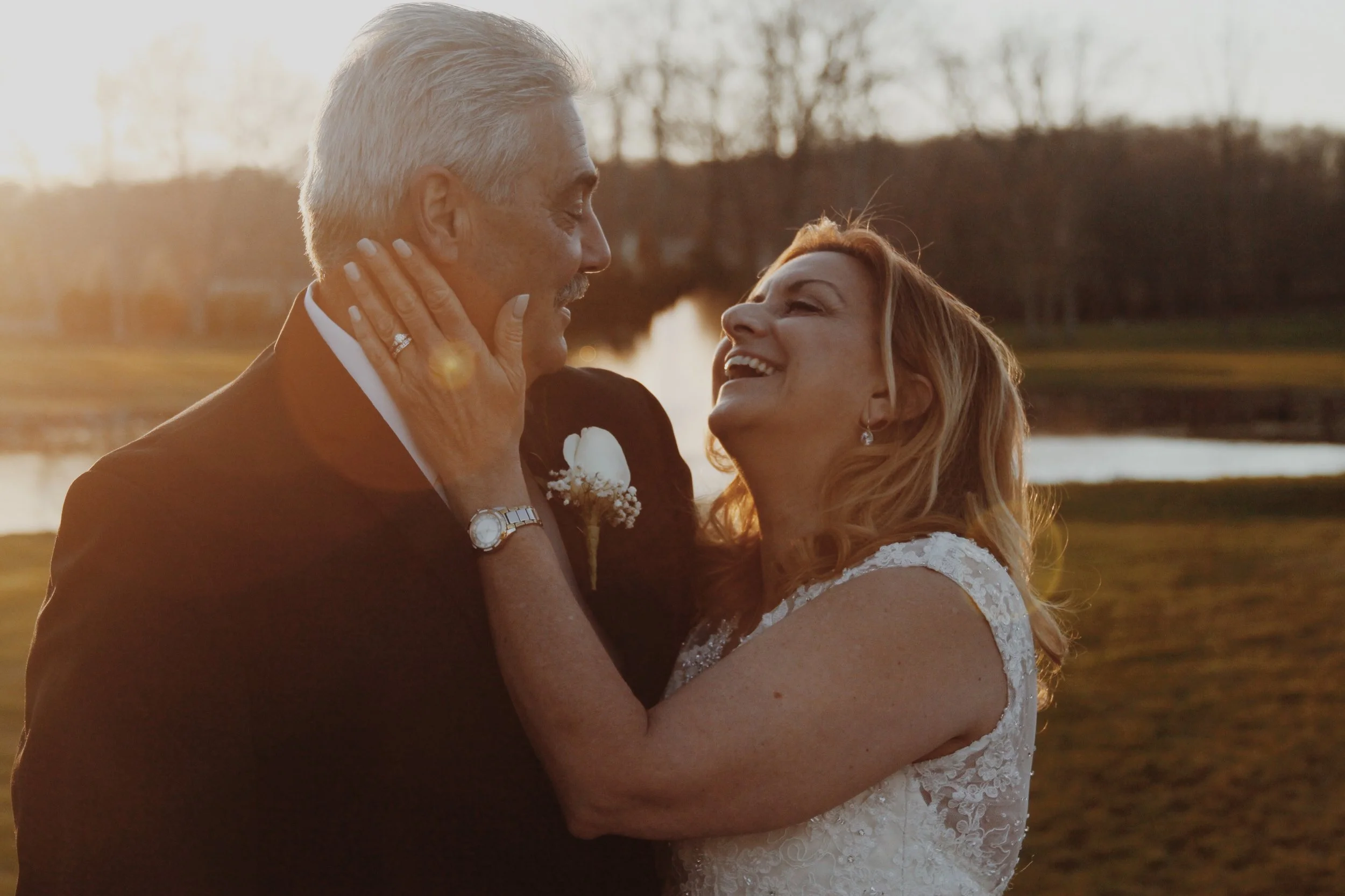 Newly married couple laughing by a lake