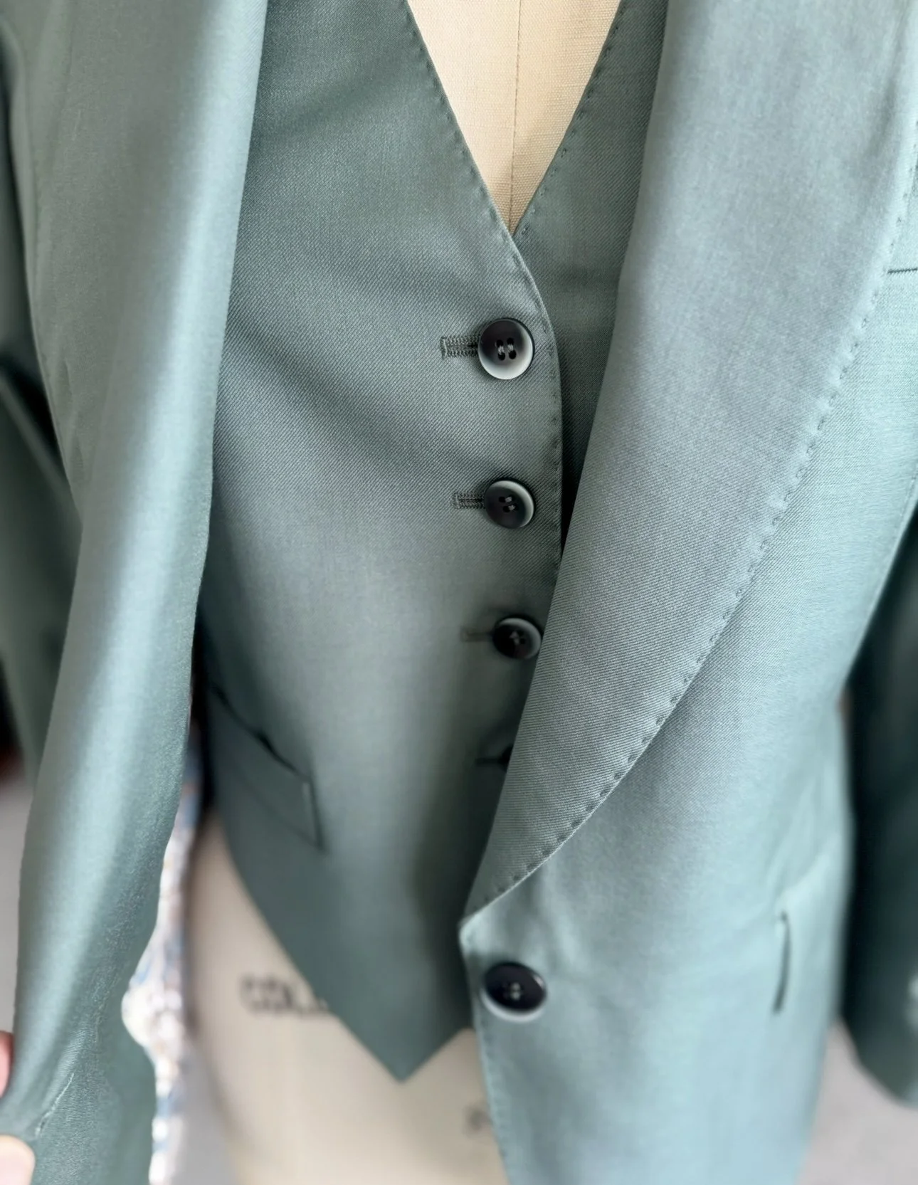 Detail of waistcoat and jacket closure with mother-of-pearl buttons on bespoke women’s moss green suit by Cutting Room Bespoke Los Angele